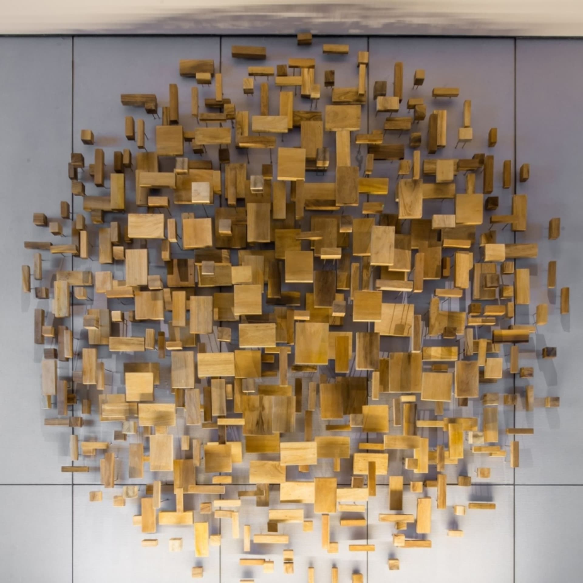 An abstract artwork installation featuring various wooden blocks arranged in a geometric pattern on a wall.
