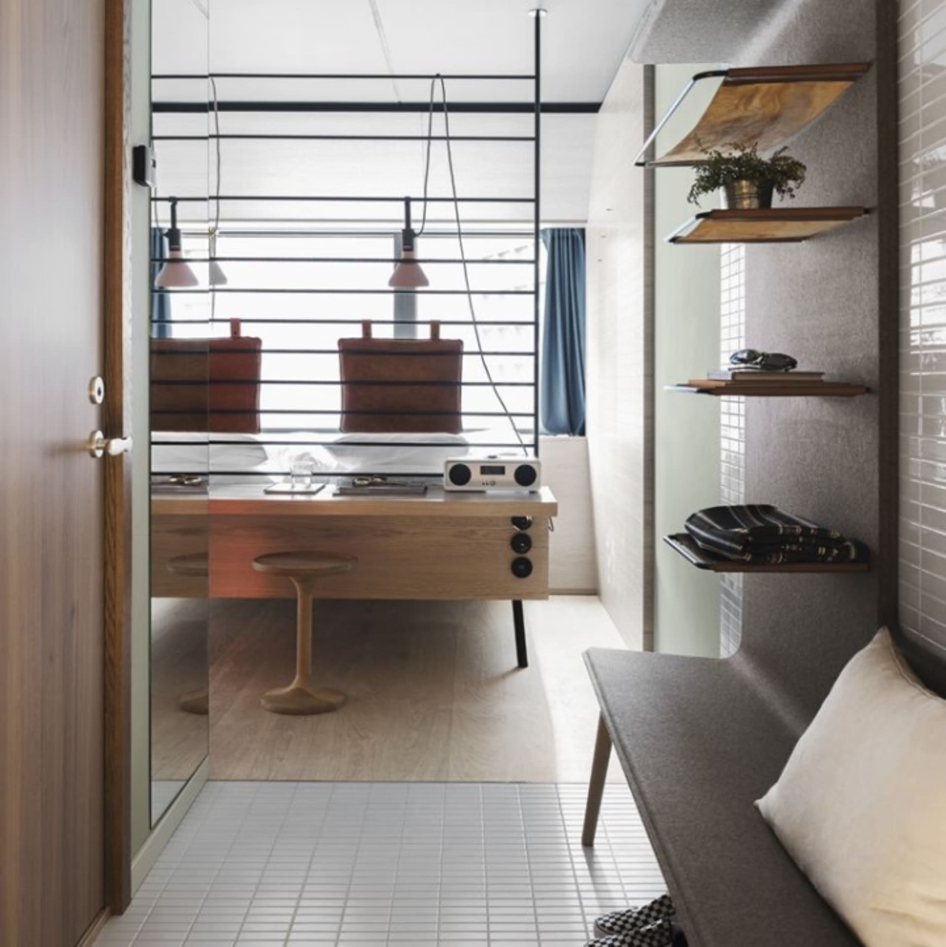 Modern minimalist office with wood desk, glass partition, and metal accents.