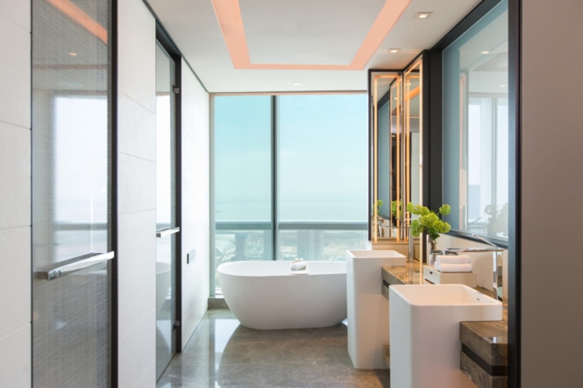 A modern bathroom featuring a white marble tub, sinks, and a glass enclosed shower.