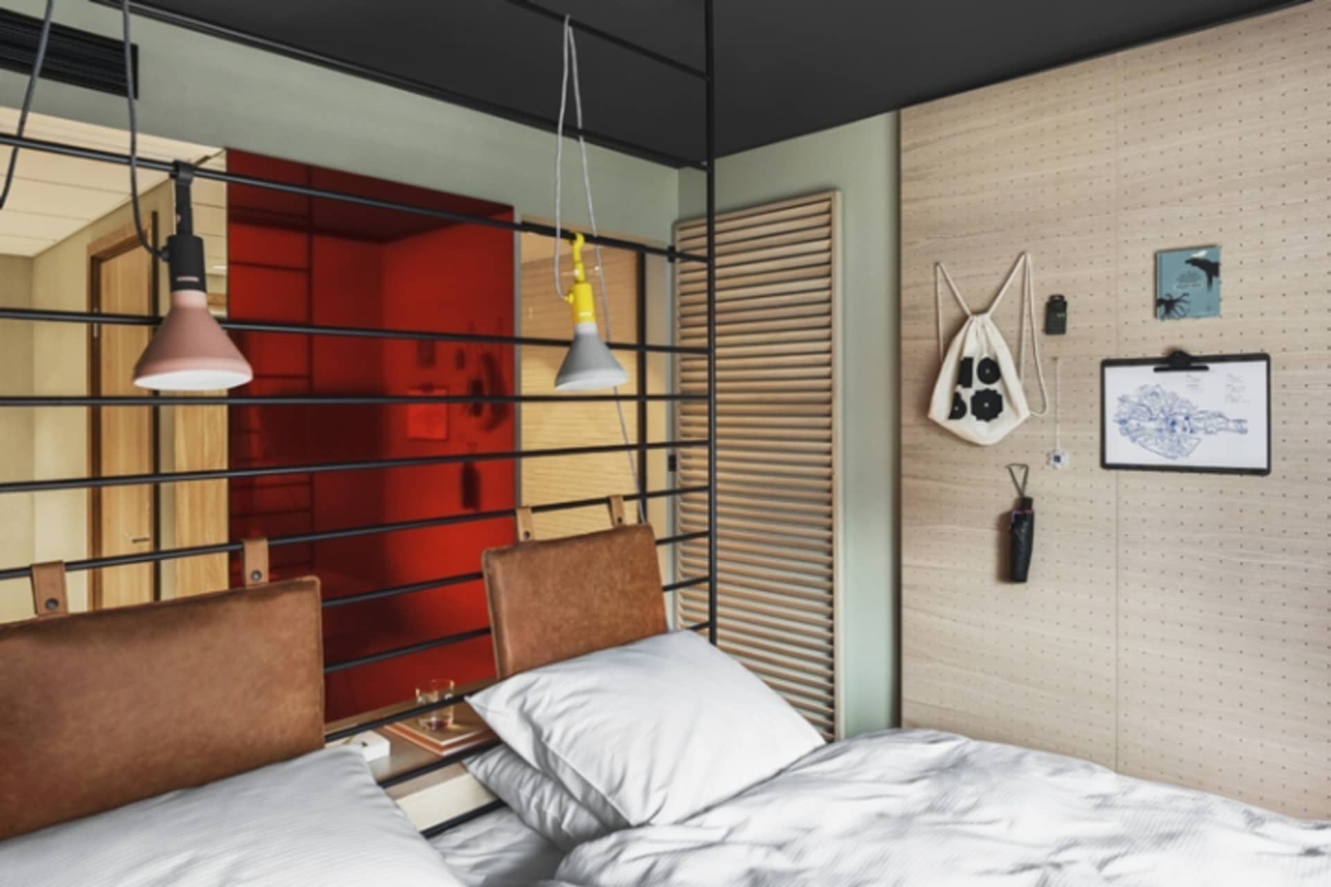 A modern bedroom featuring a leather headboard on the bed, against a red background with hanging lights and pegboard storage.