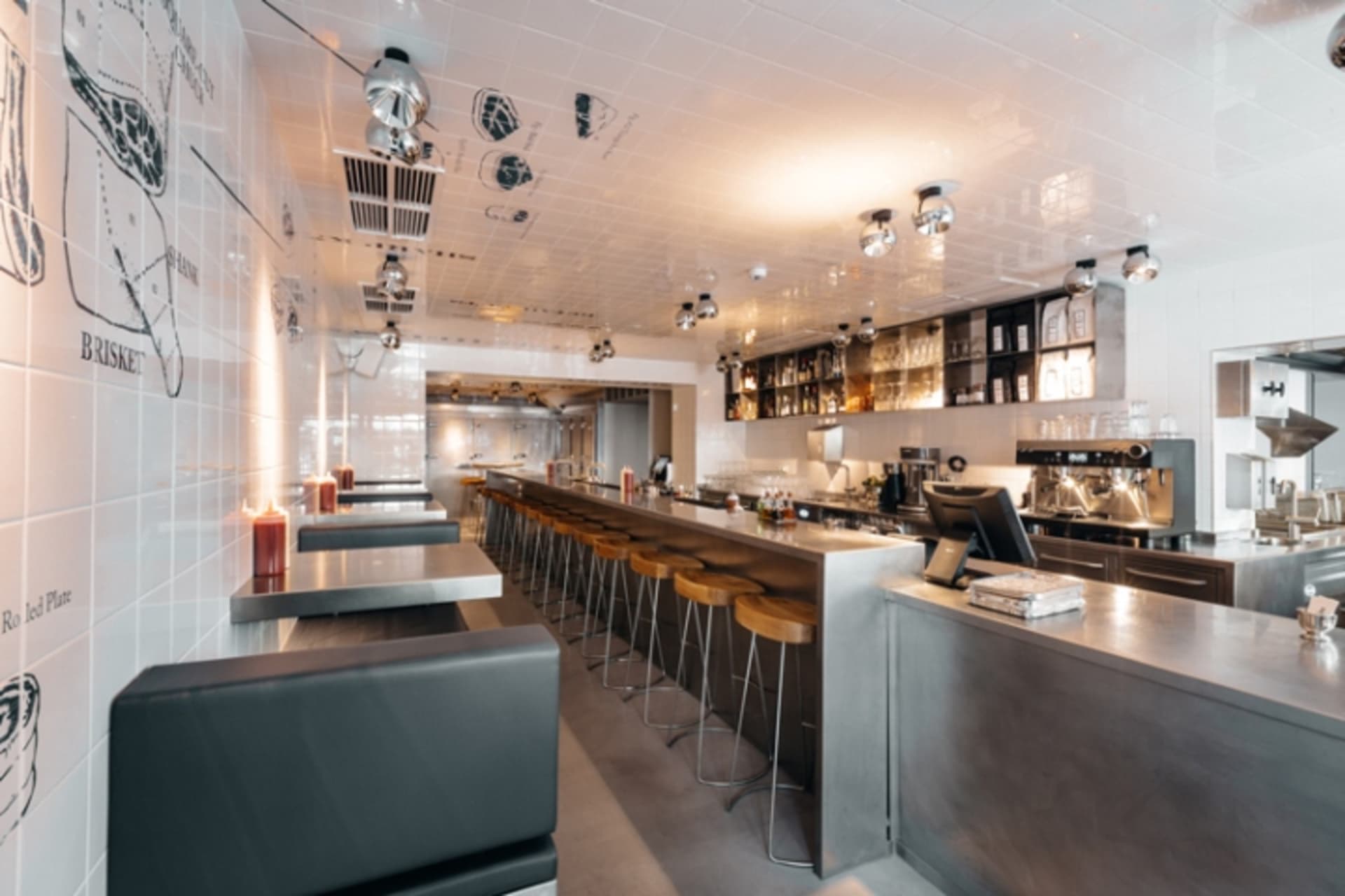 A modern industrial kitchen with metal stools and concrete countertops.