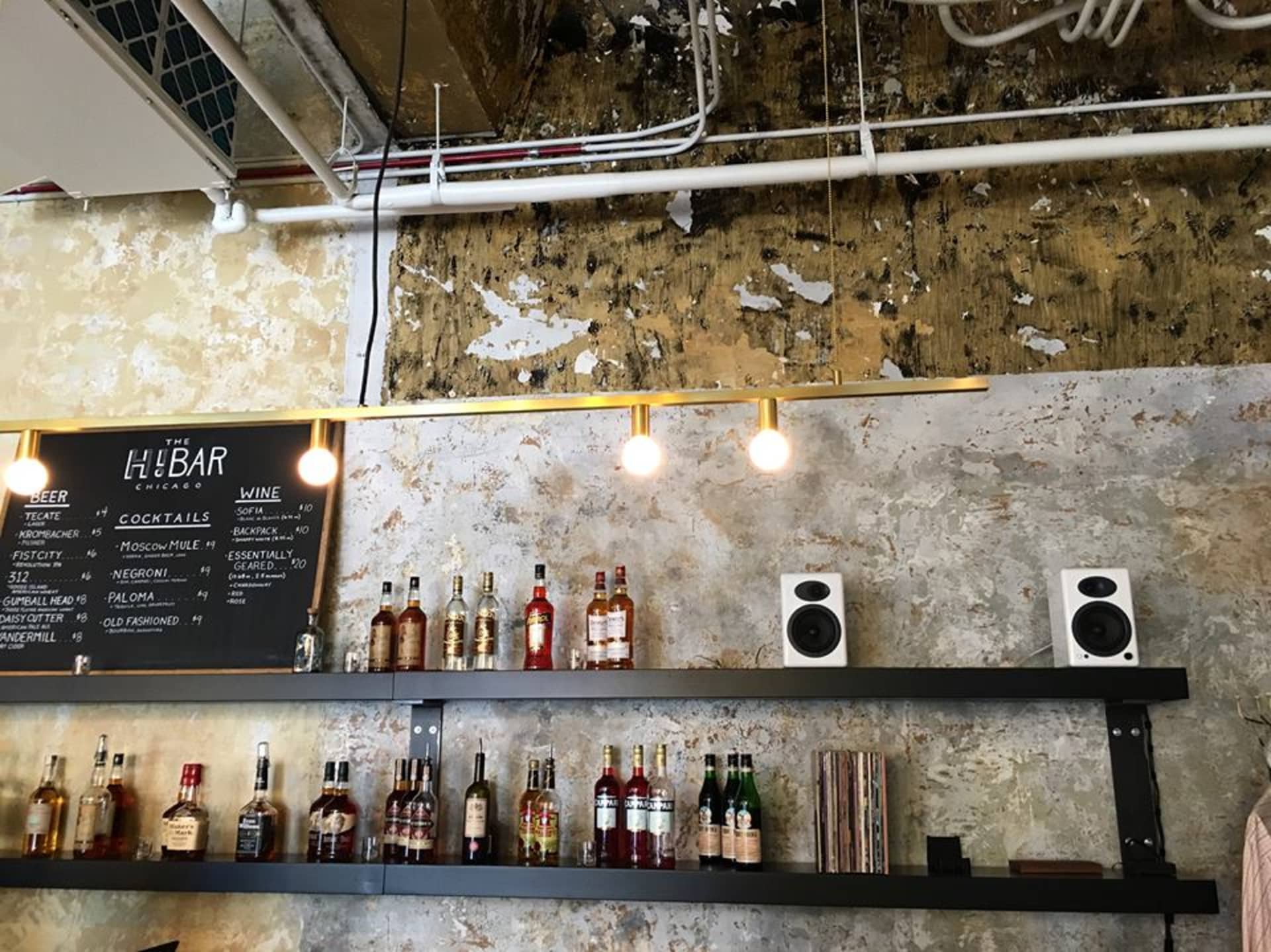 Bar area with bottles and speakers on shelves.