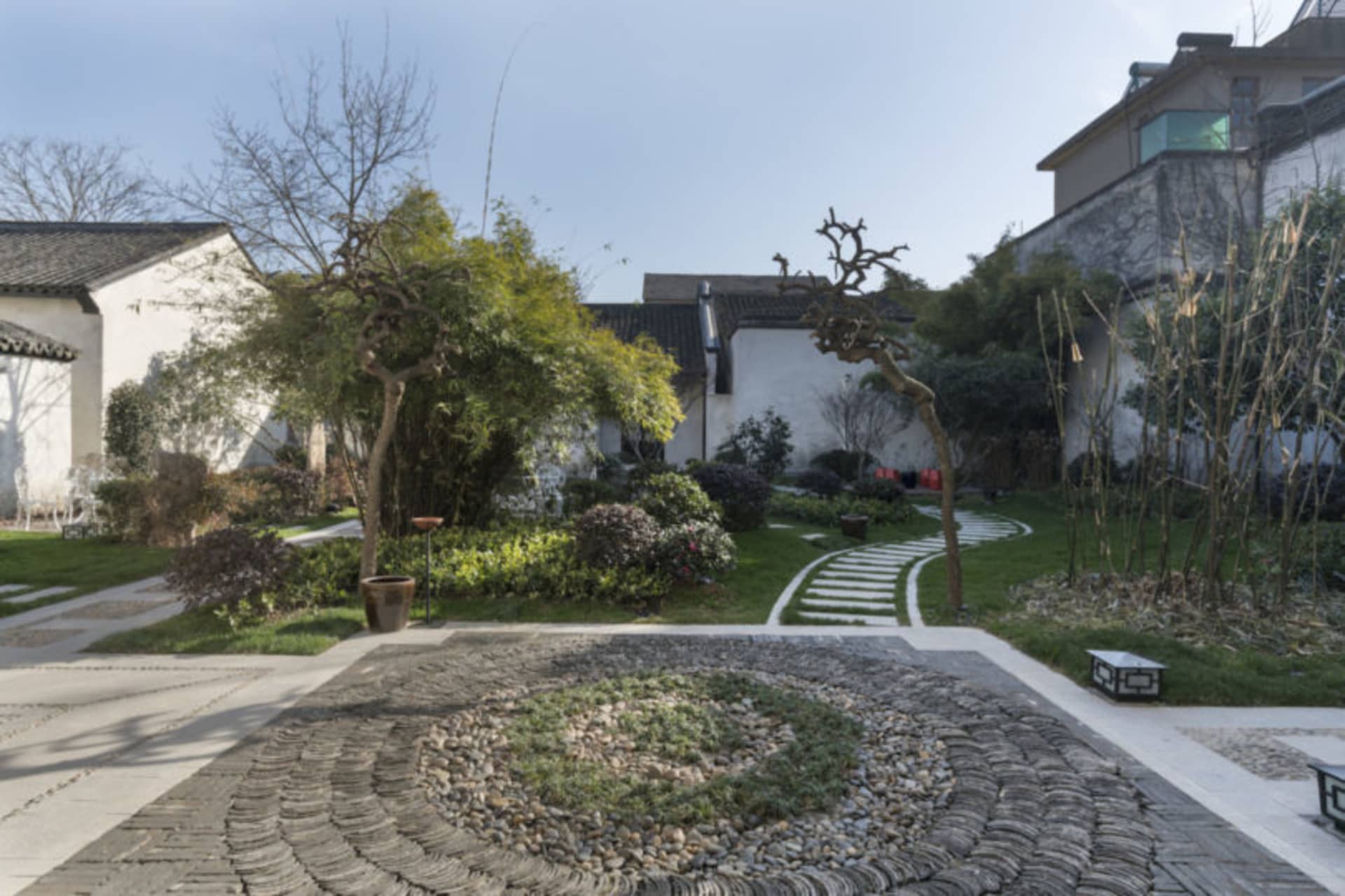 寧靜的花園，佈滿天然石材、草地與樹木。