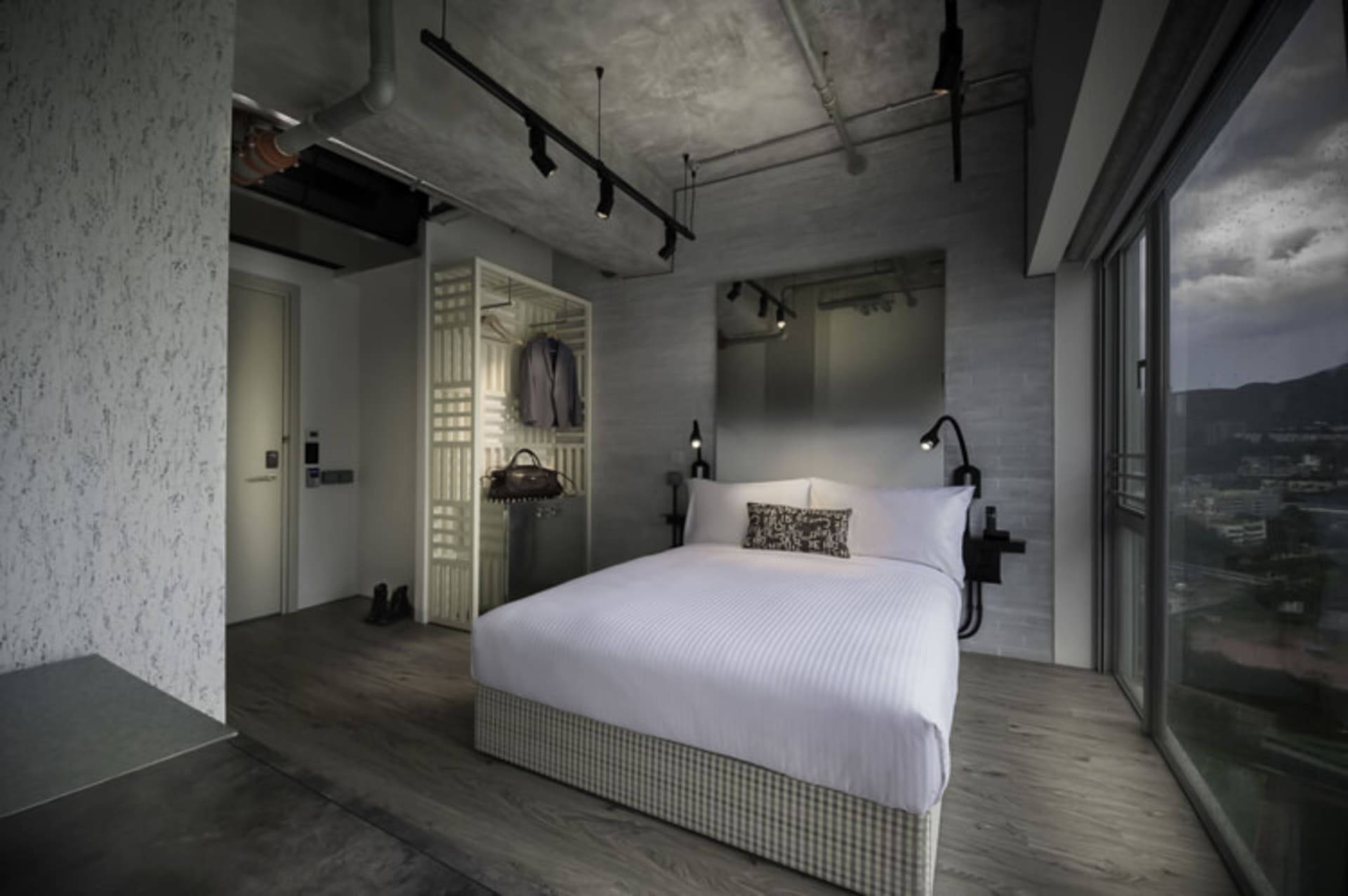 A modern industrial bedroom with concrete walls, flooring, and minimalist furniture.