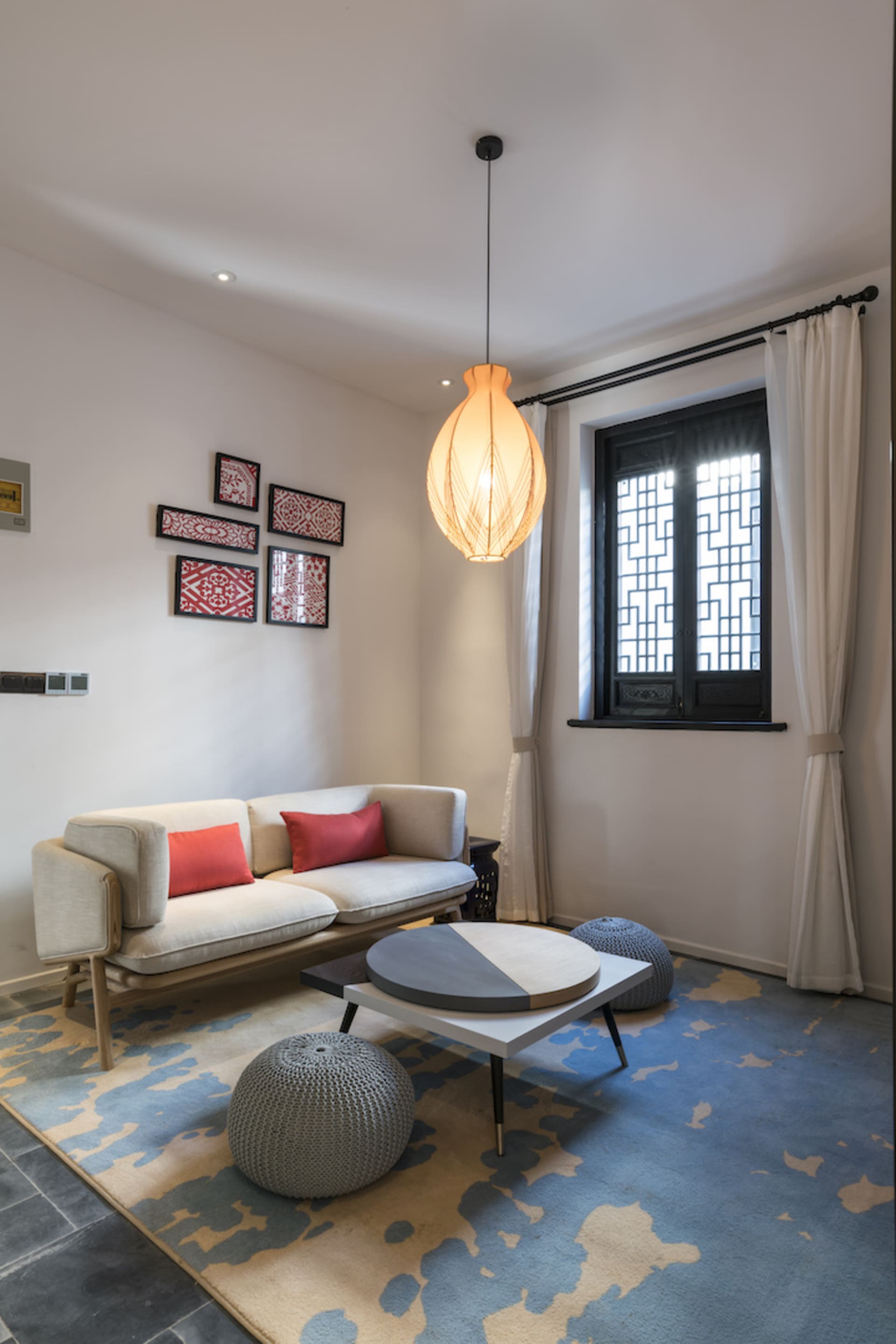 A modern living room with a geometric patterned rug, a white modular sofa with red throw pillows, and a round coffee table wi