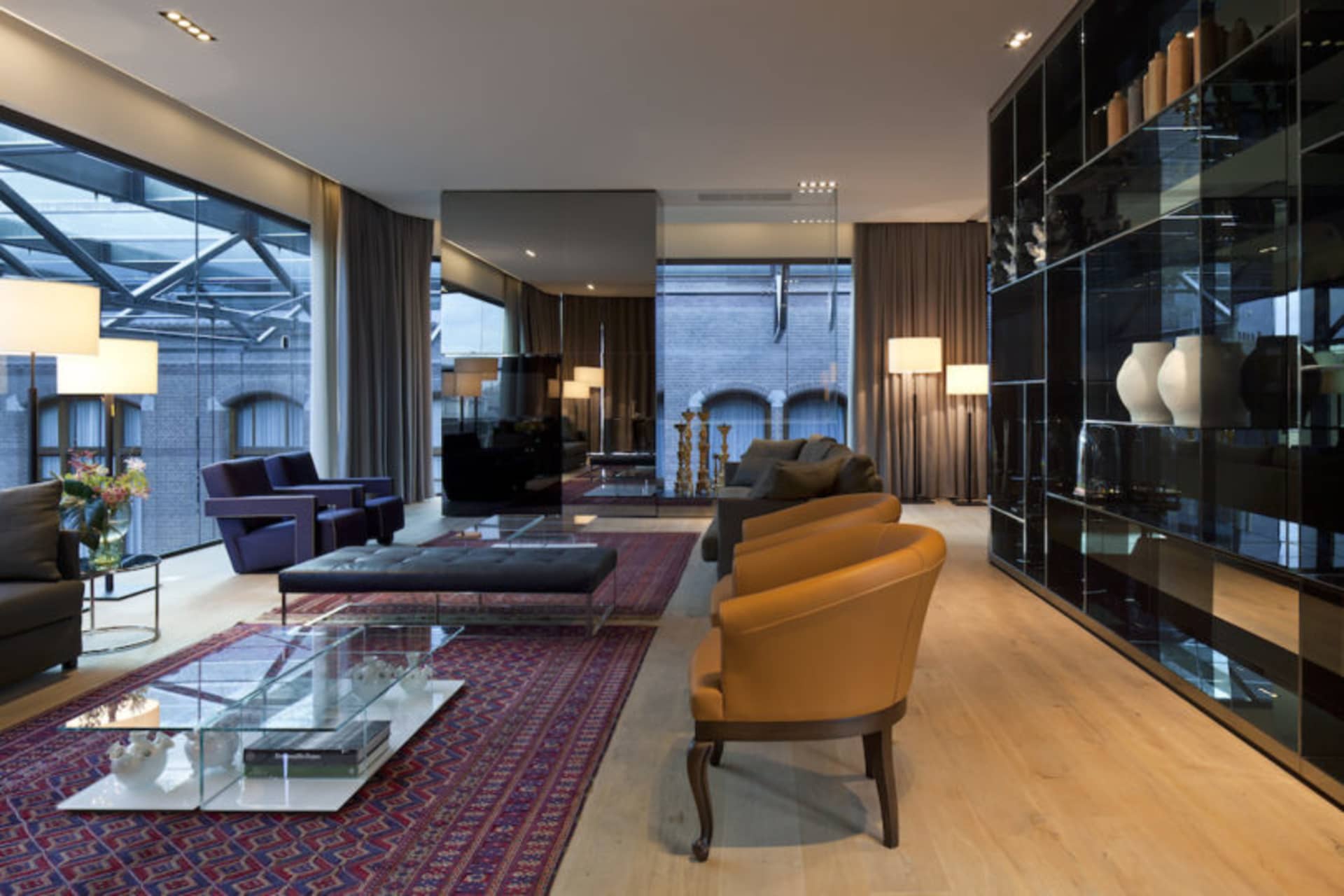 Modern living room with leather couches, glass tables, and wooden flooring.