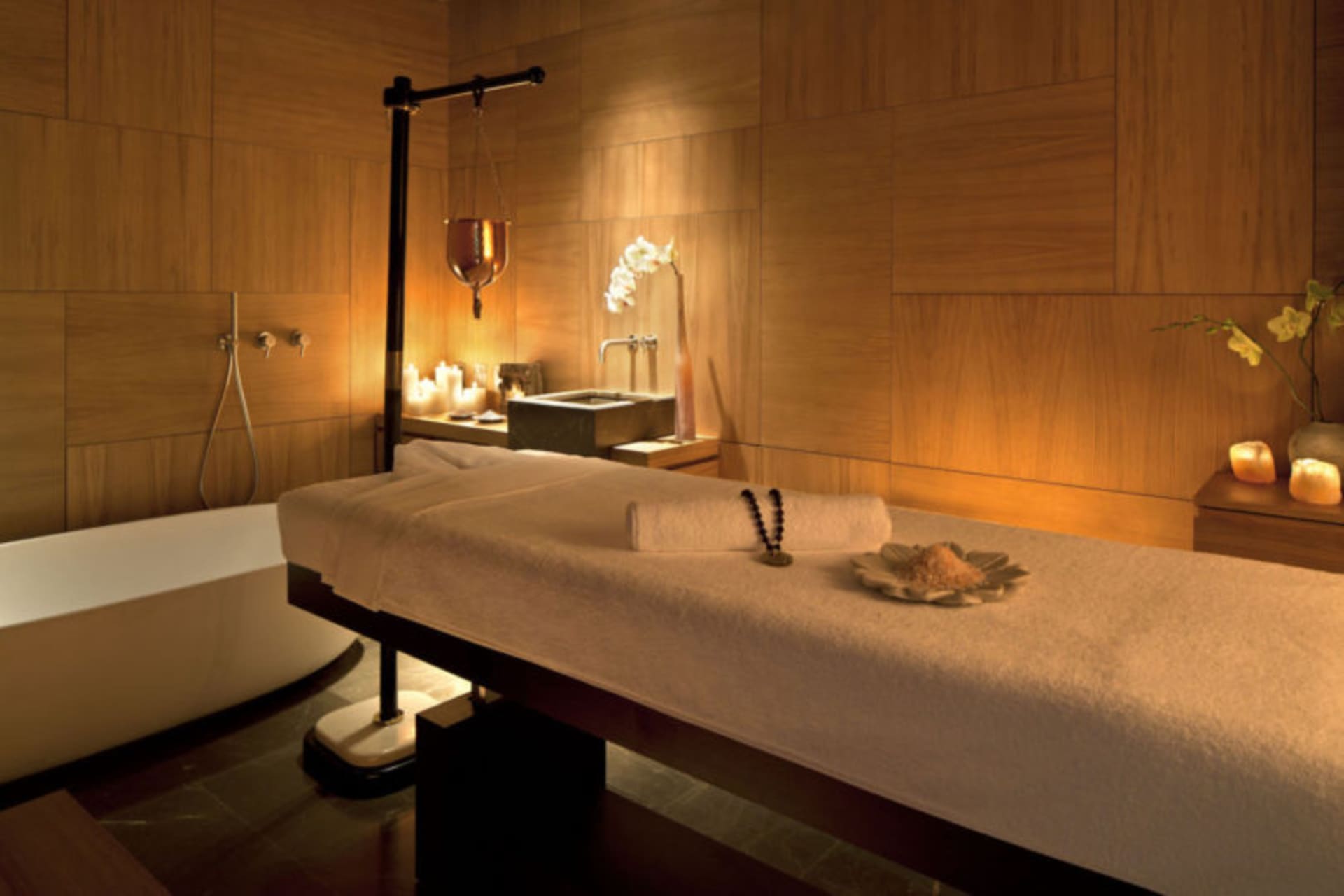 A serene spa massage room with wooden walls, candles, and a massage table.