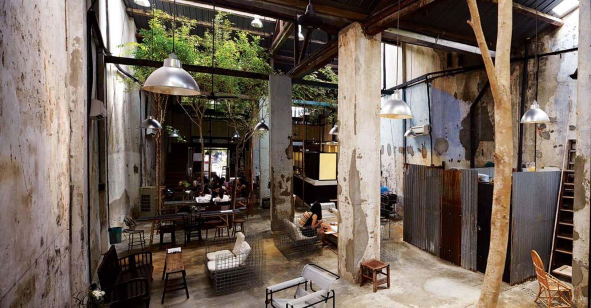 A rustic industrial cafe interior with concrete walls, steel accents, and glass partitions.