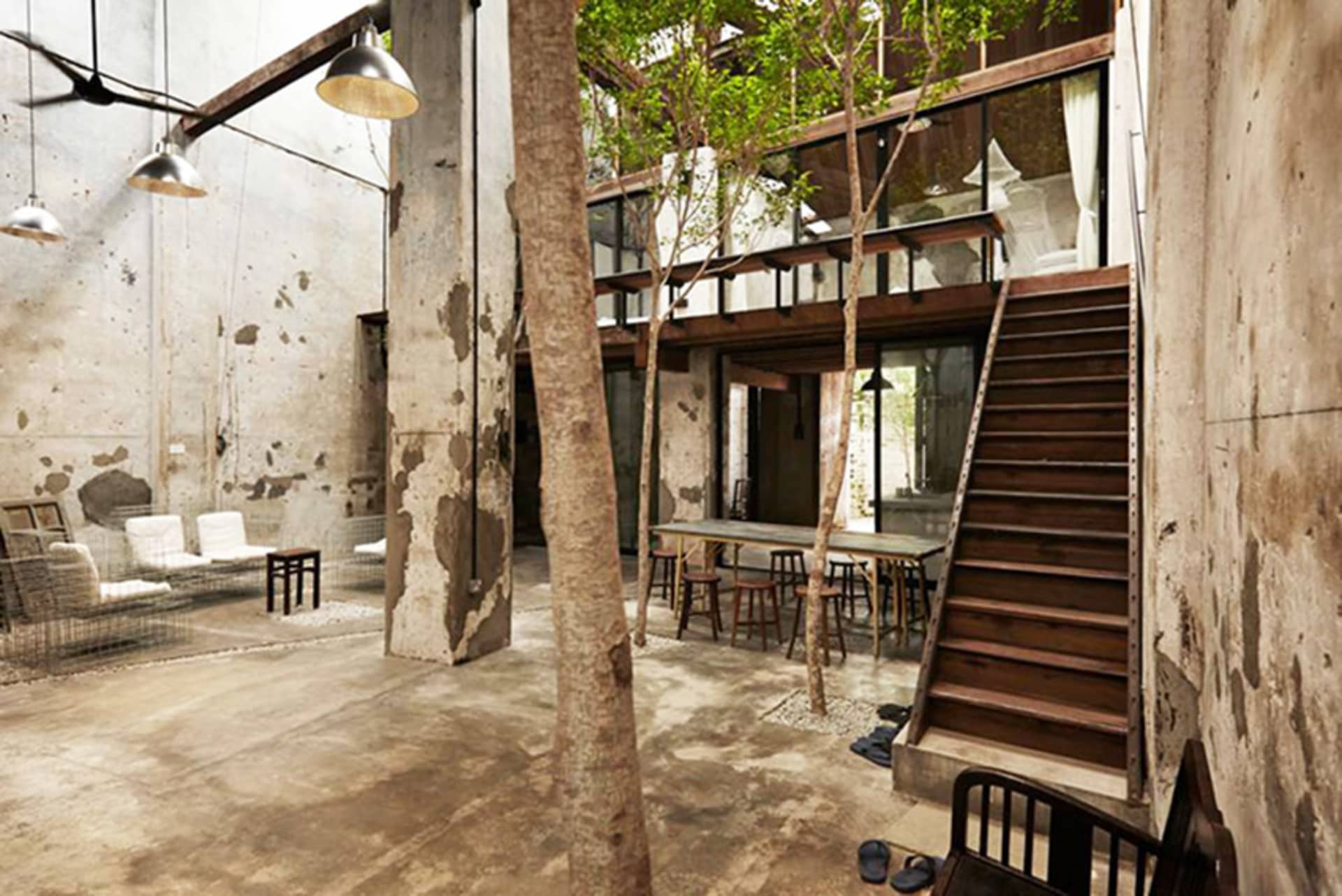 An industrial-minimalist living room with concrete walls, wooden furniture, and steel accents.