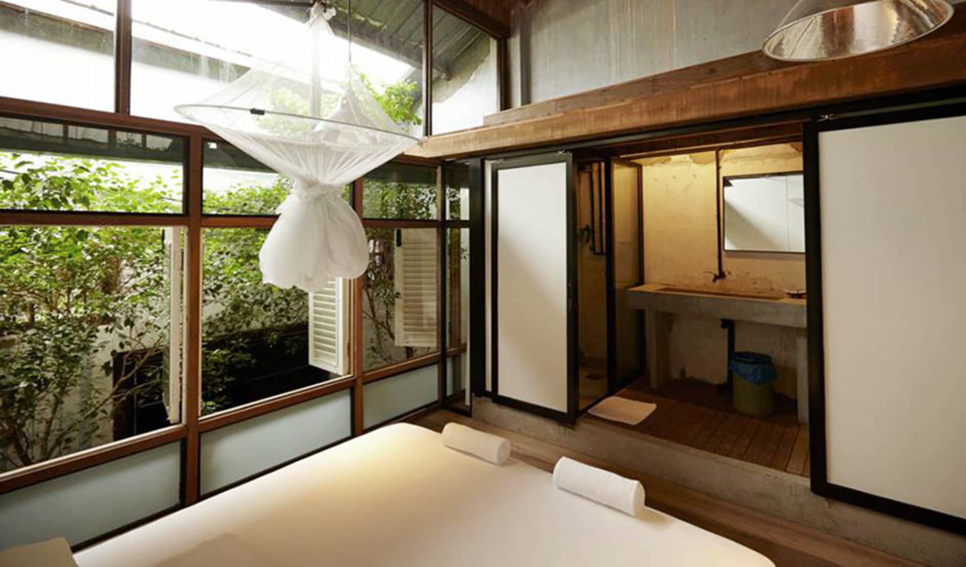 Modern bedroom with a chandelier over the bed and a concrete finish.