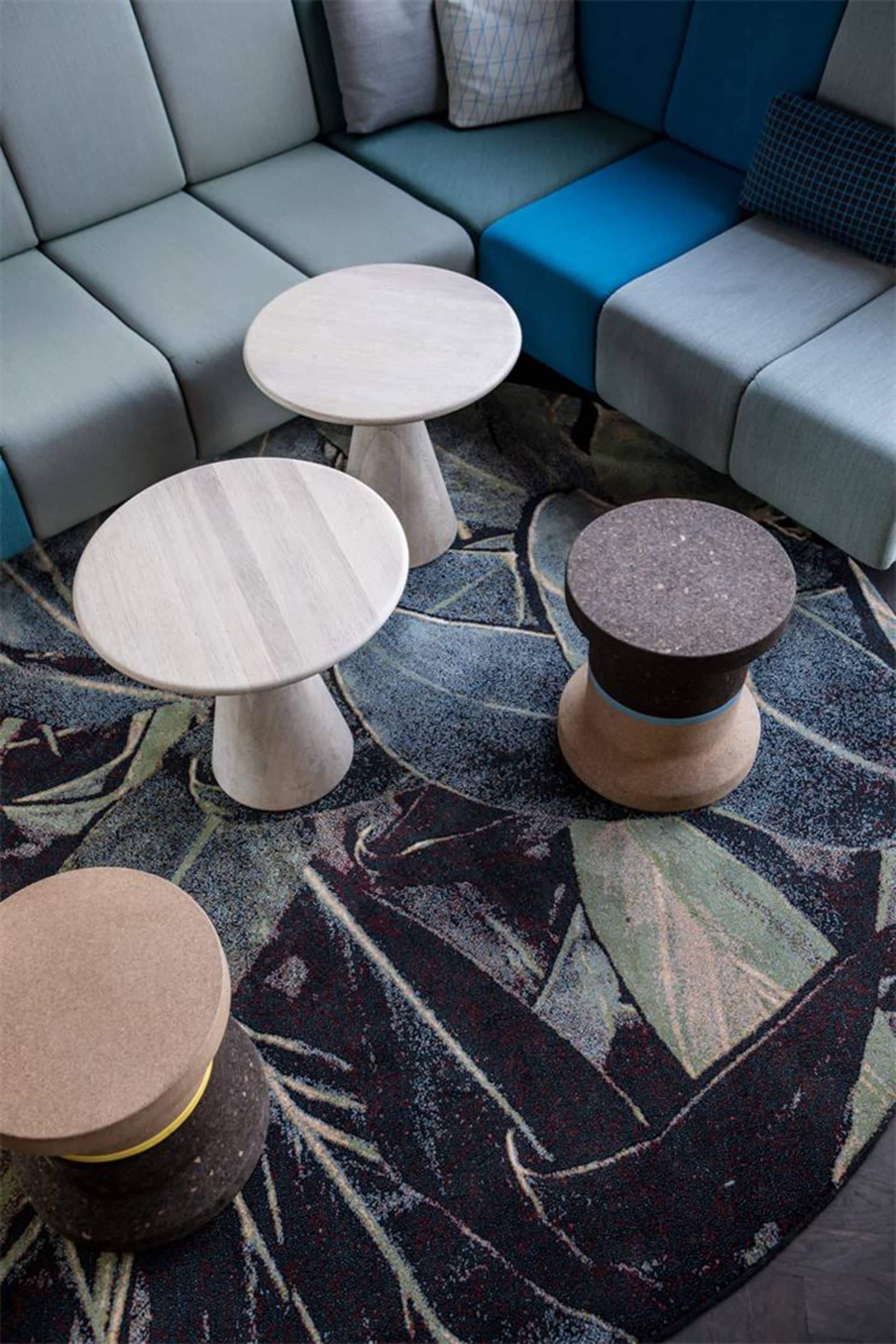A modern seating area with flat-pack concrete furniture on a patterned rug.