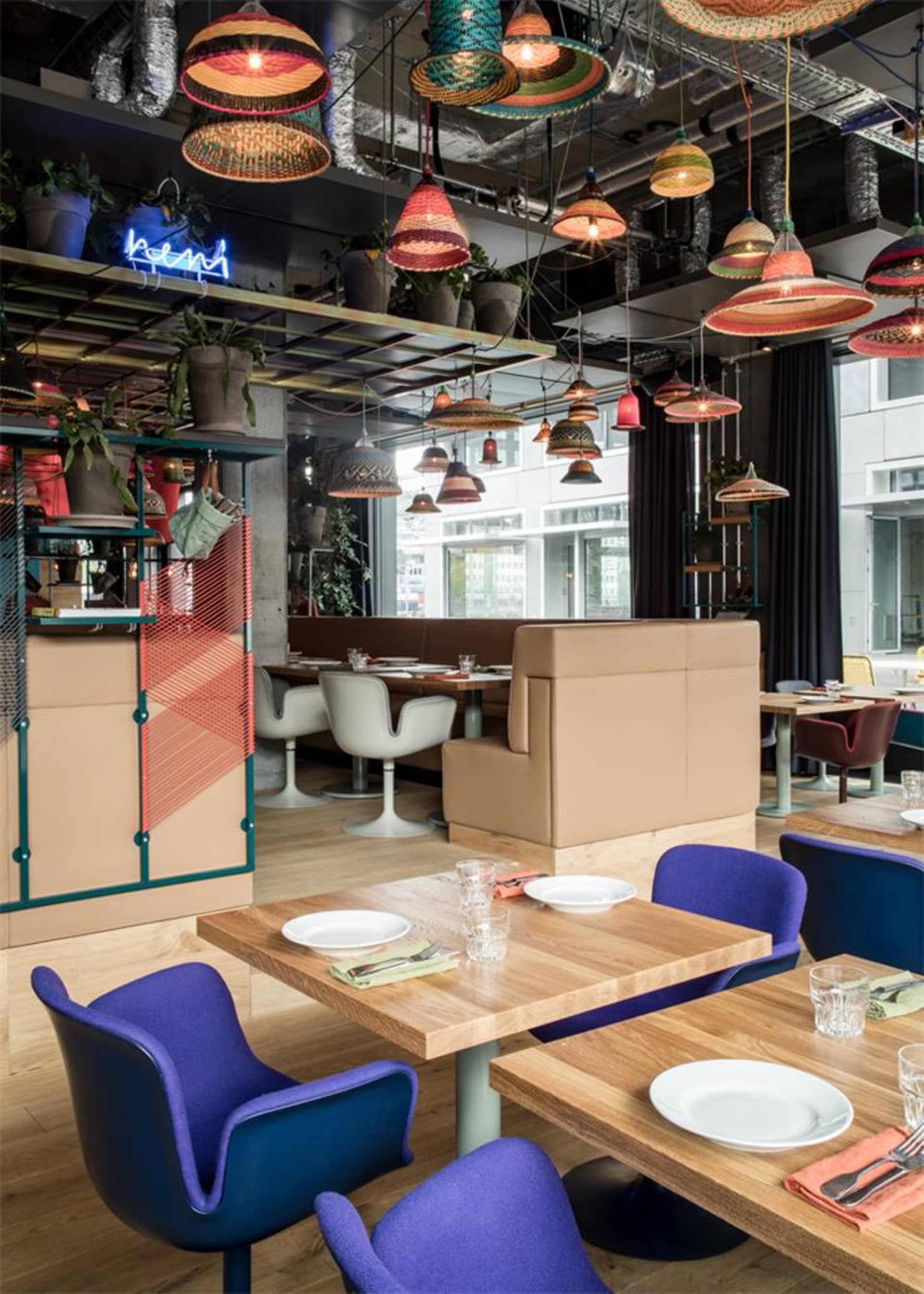 A modern restaurant interior with wooden tables, fabric chairs, and metal accents.
