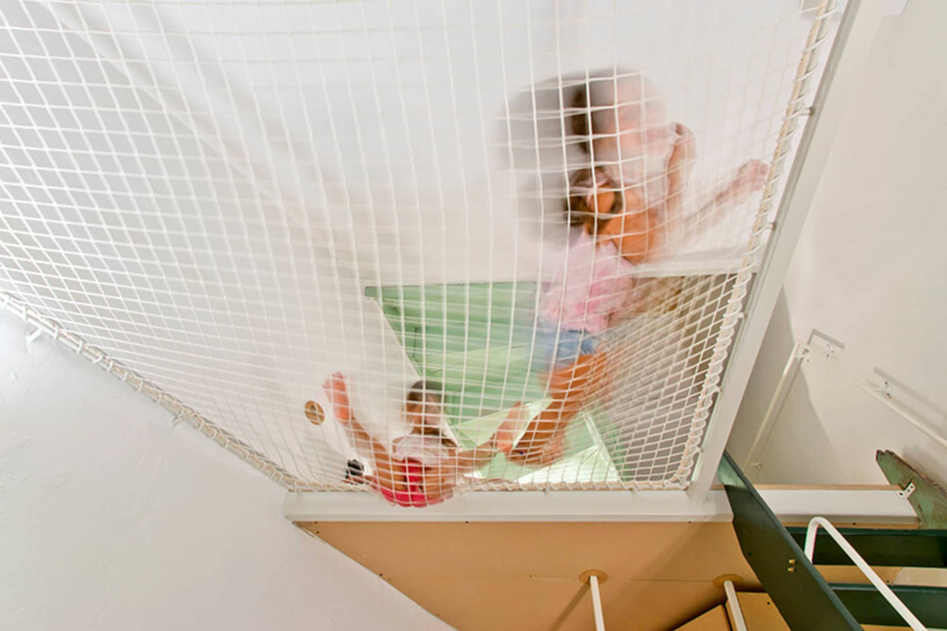 一名幼童在兒童房遊戲區攀爬安全網。