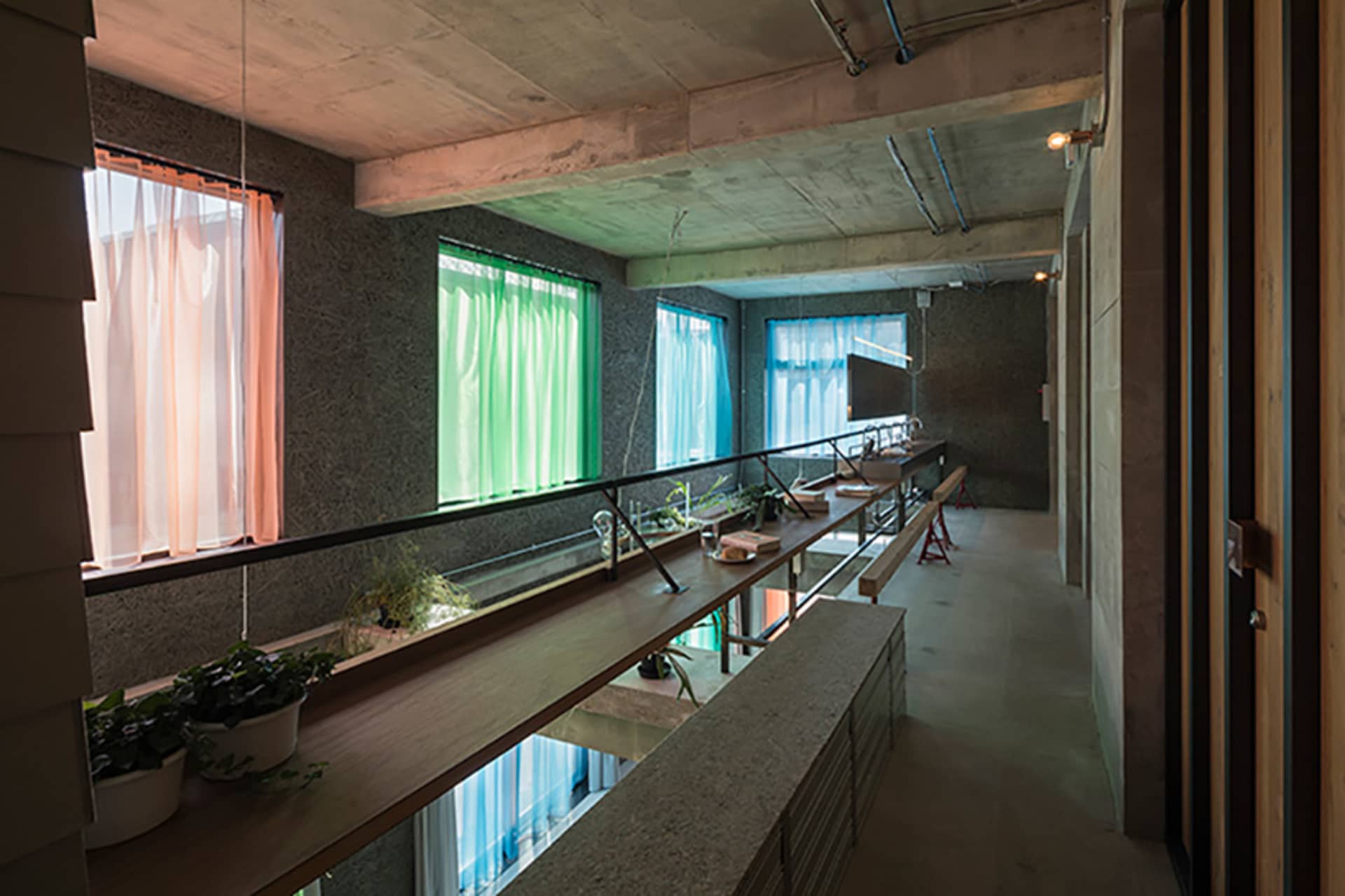 Industrial-style interior with concrete walls and green curtains.