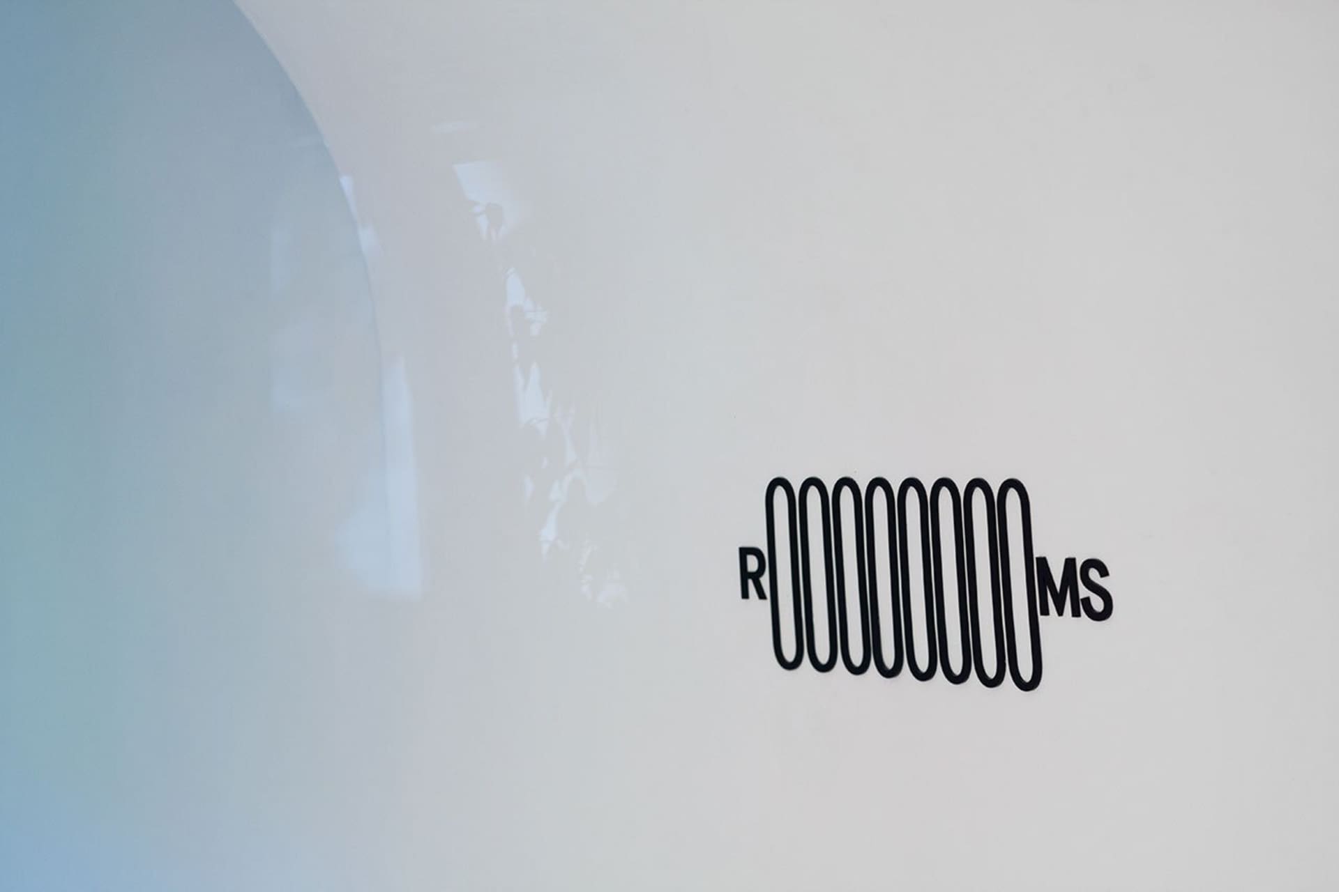 A minimalist logo design featuring a metallic representation of the letters RMMS on a white background.