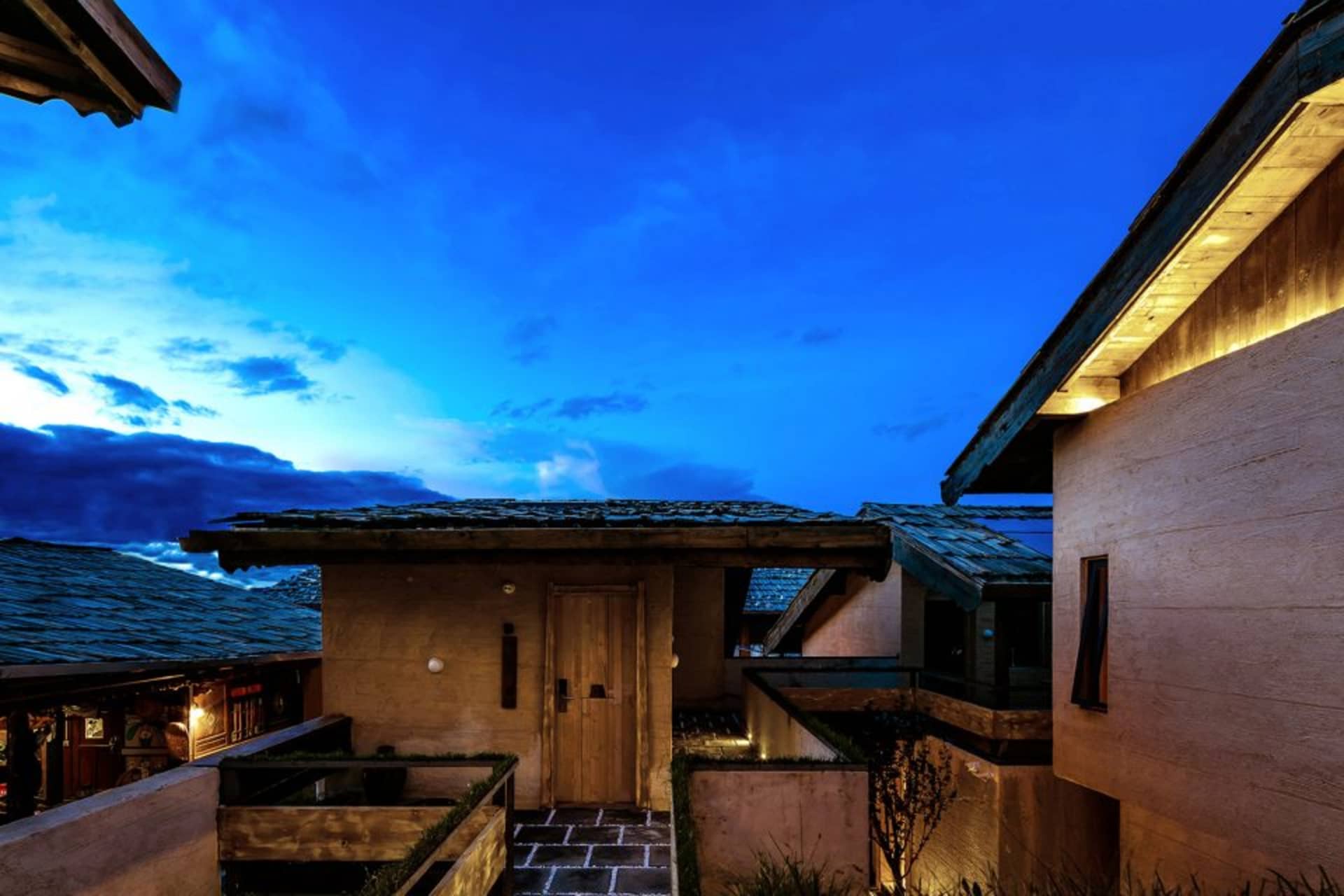 夜間住宅建築外觀，搭配木質板材與照明石板步道。