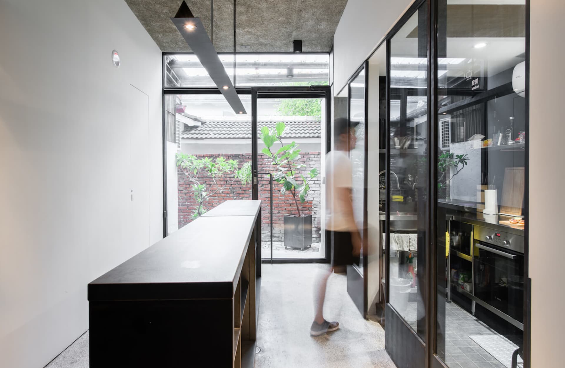 A modern kitchen with glass walls and concrete flooring and ceiling.