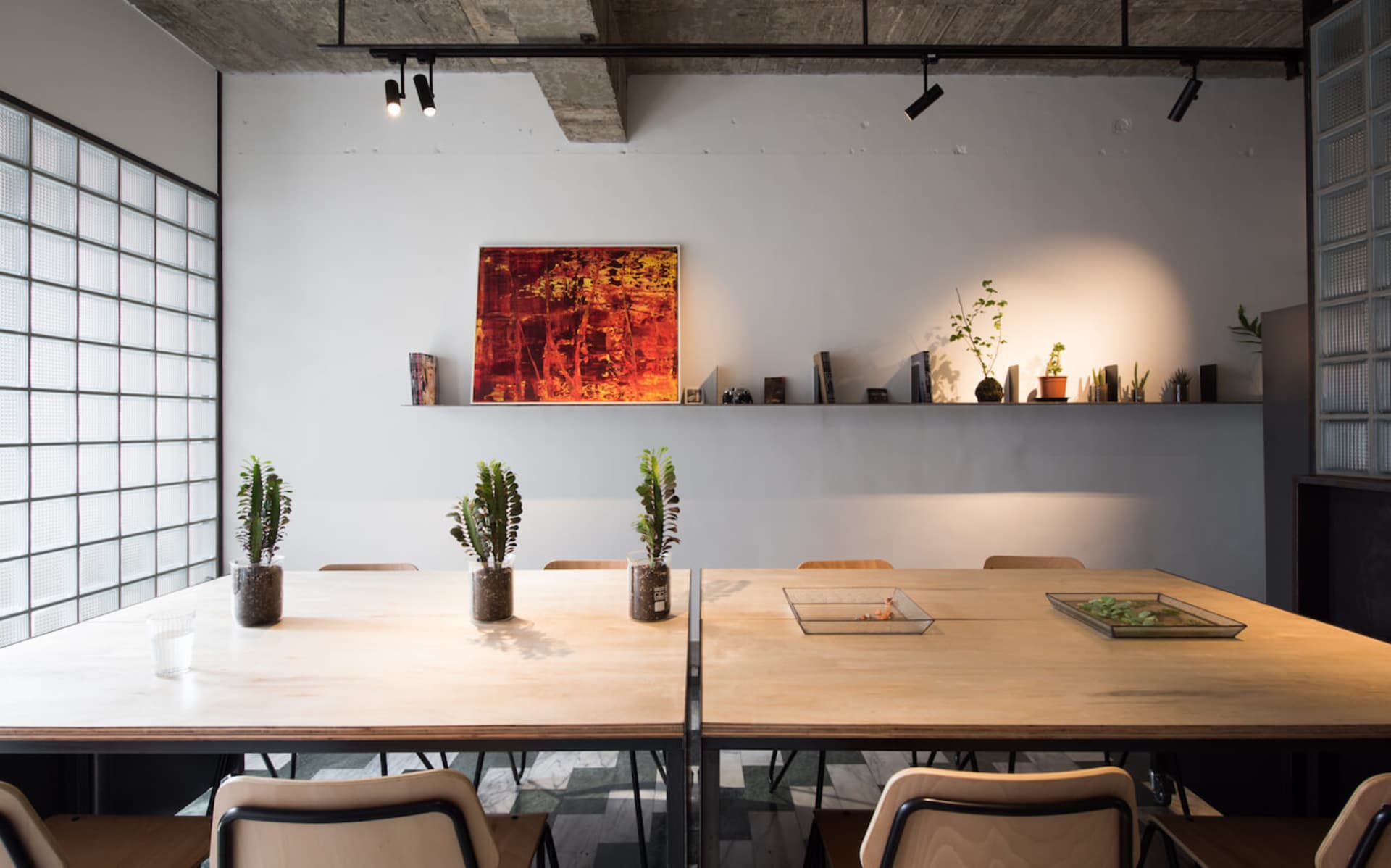 Modern office space with wooden furniture, plants, and a colorful abstract painting on the wall.