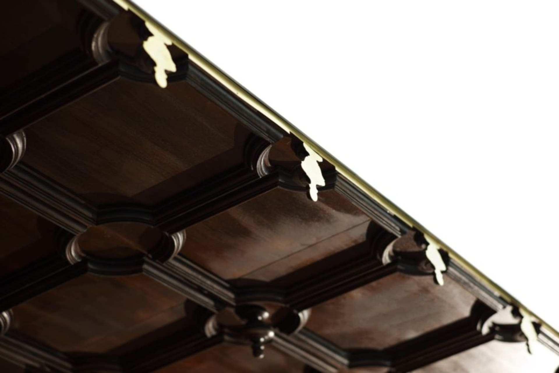 A segment of a wooden roof beam structure adorned with an elegant brass decorative edge.
