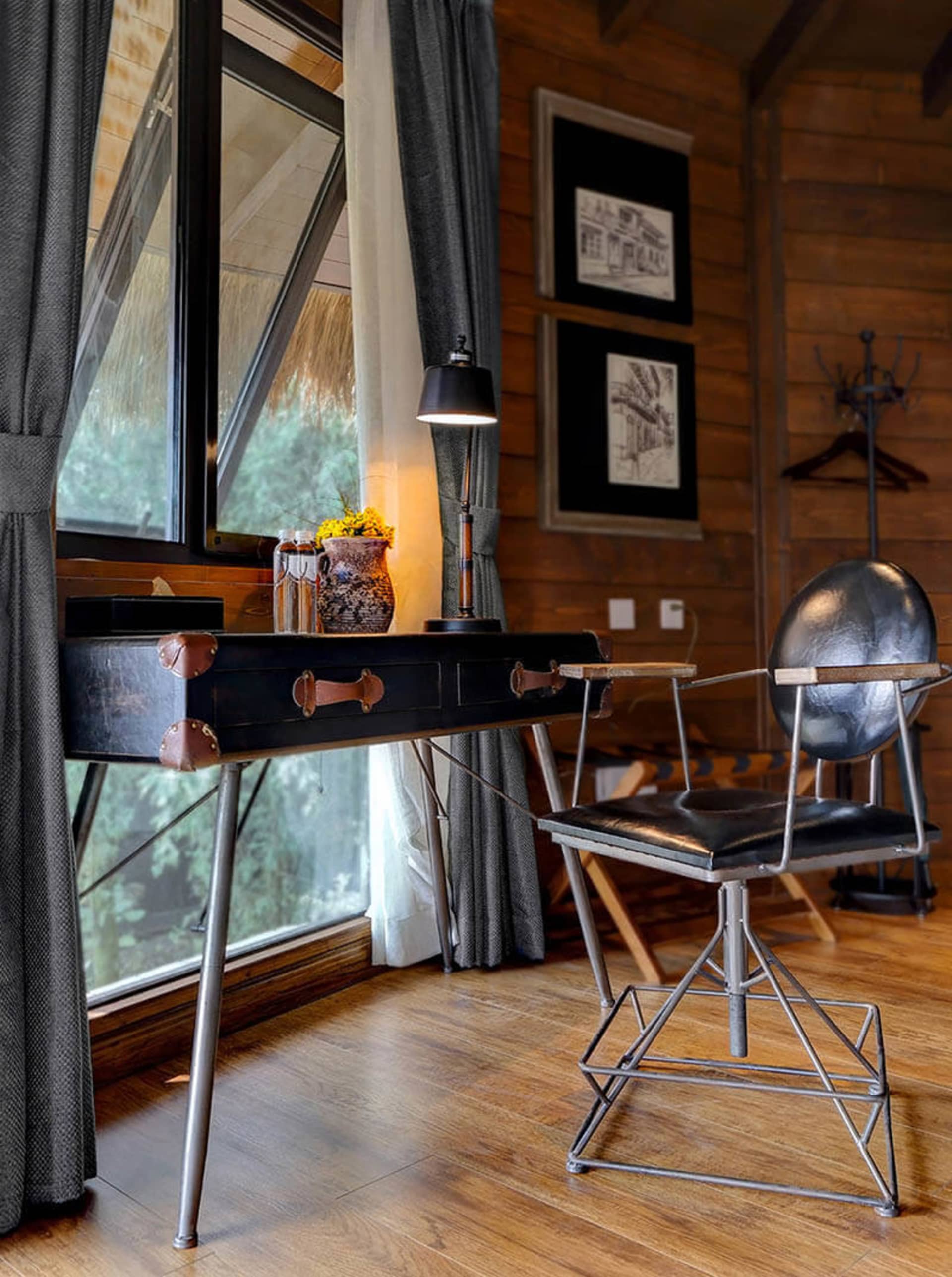 Industrial-style office space featuring a black, metallic desk frame with leather handles, a black cushioned metal chair, and