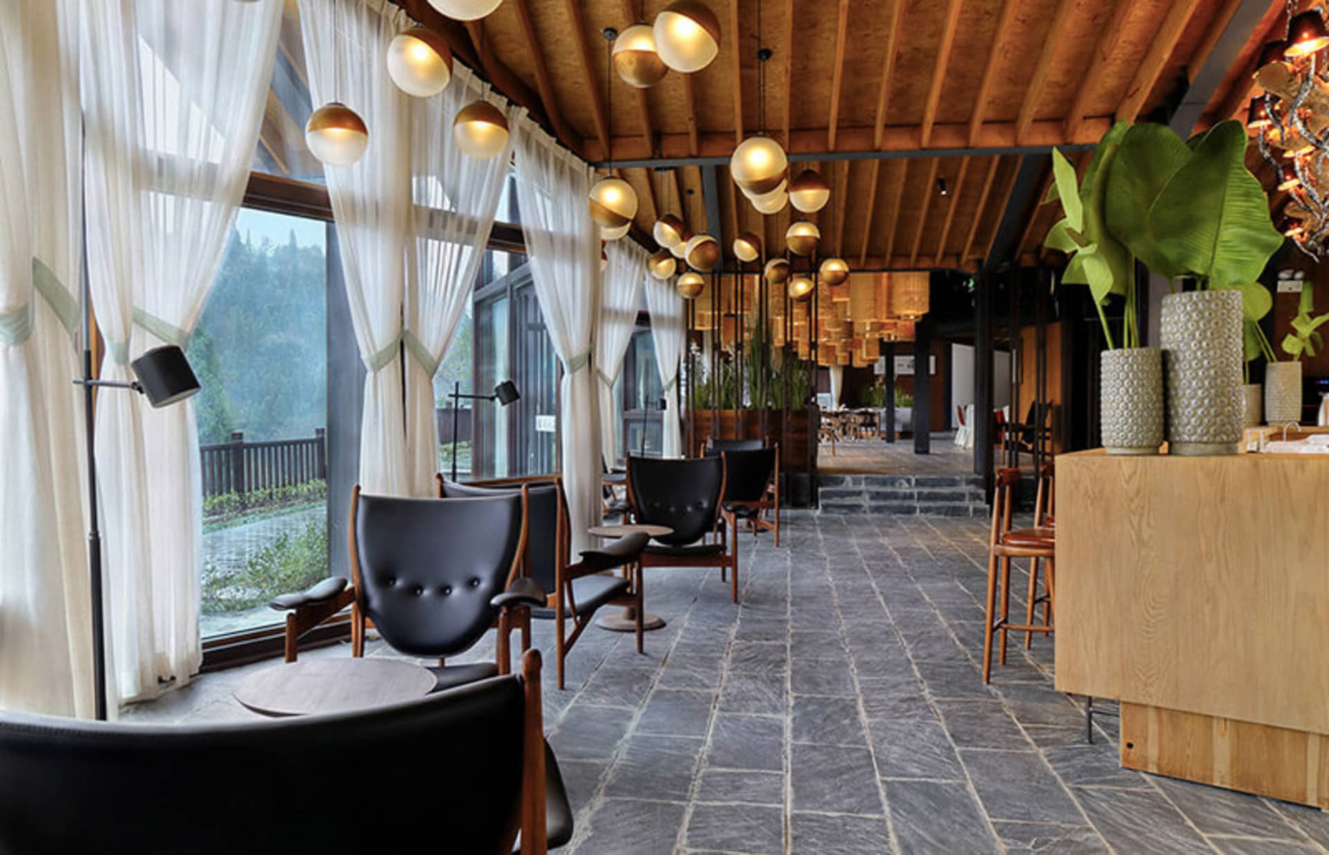 Industrial-style restaurant interior with stone flooring and leather upholstery on chairs.