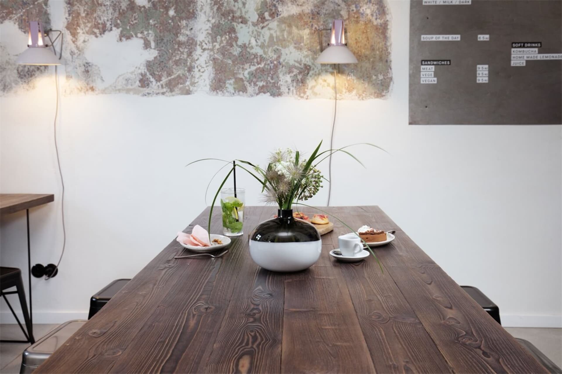 A wooden table adorned with flowers and food in a cafe setting.