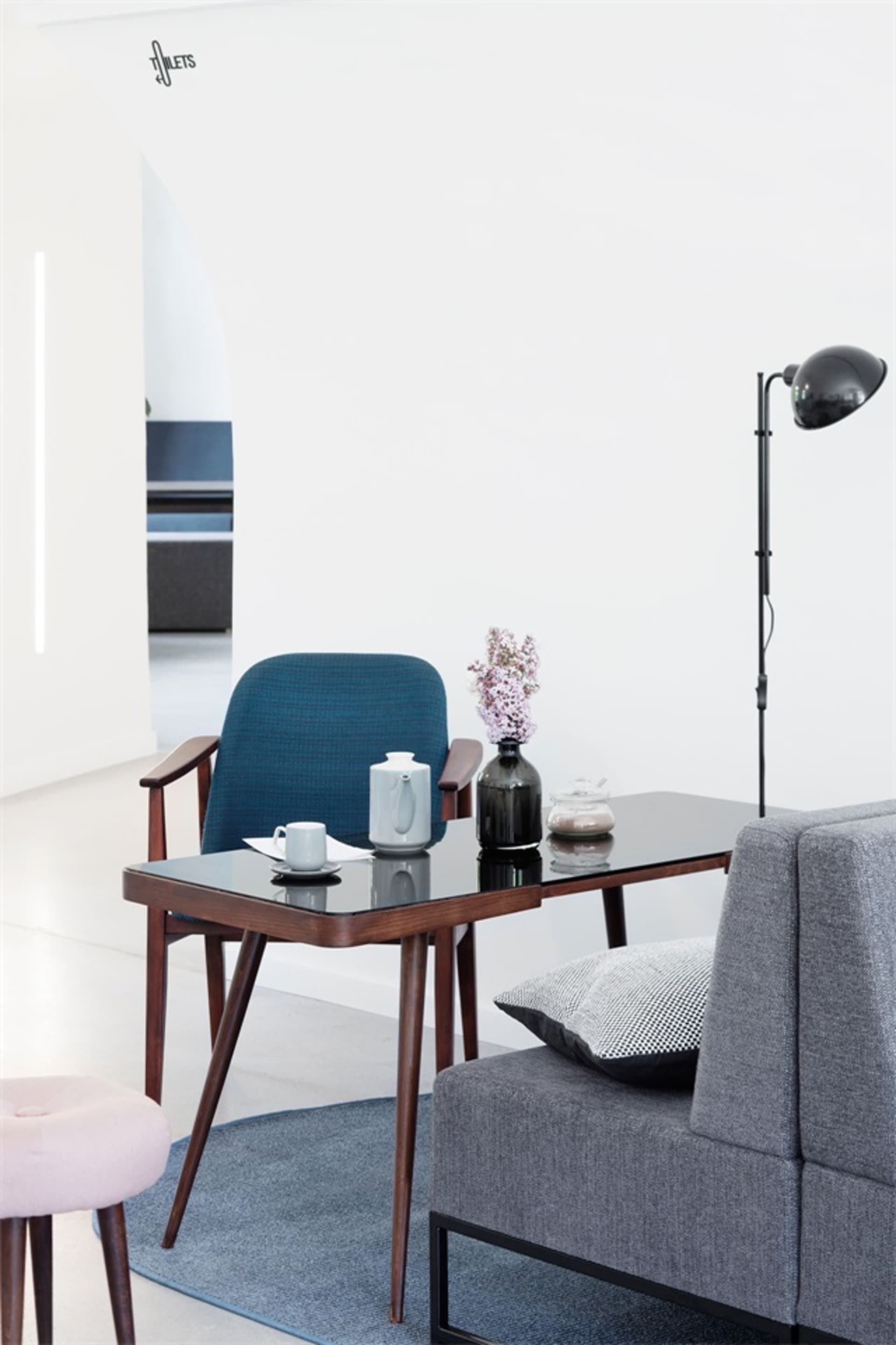 A modern living room featuring a leg table and couch, with a vase of flowers and a lamp.
