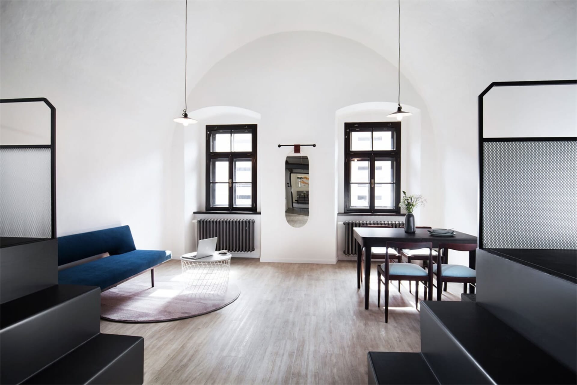 A modern living room with wooden floors, a blue sofa, and metal accents.