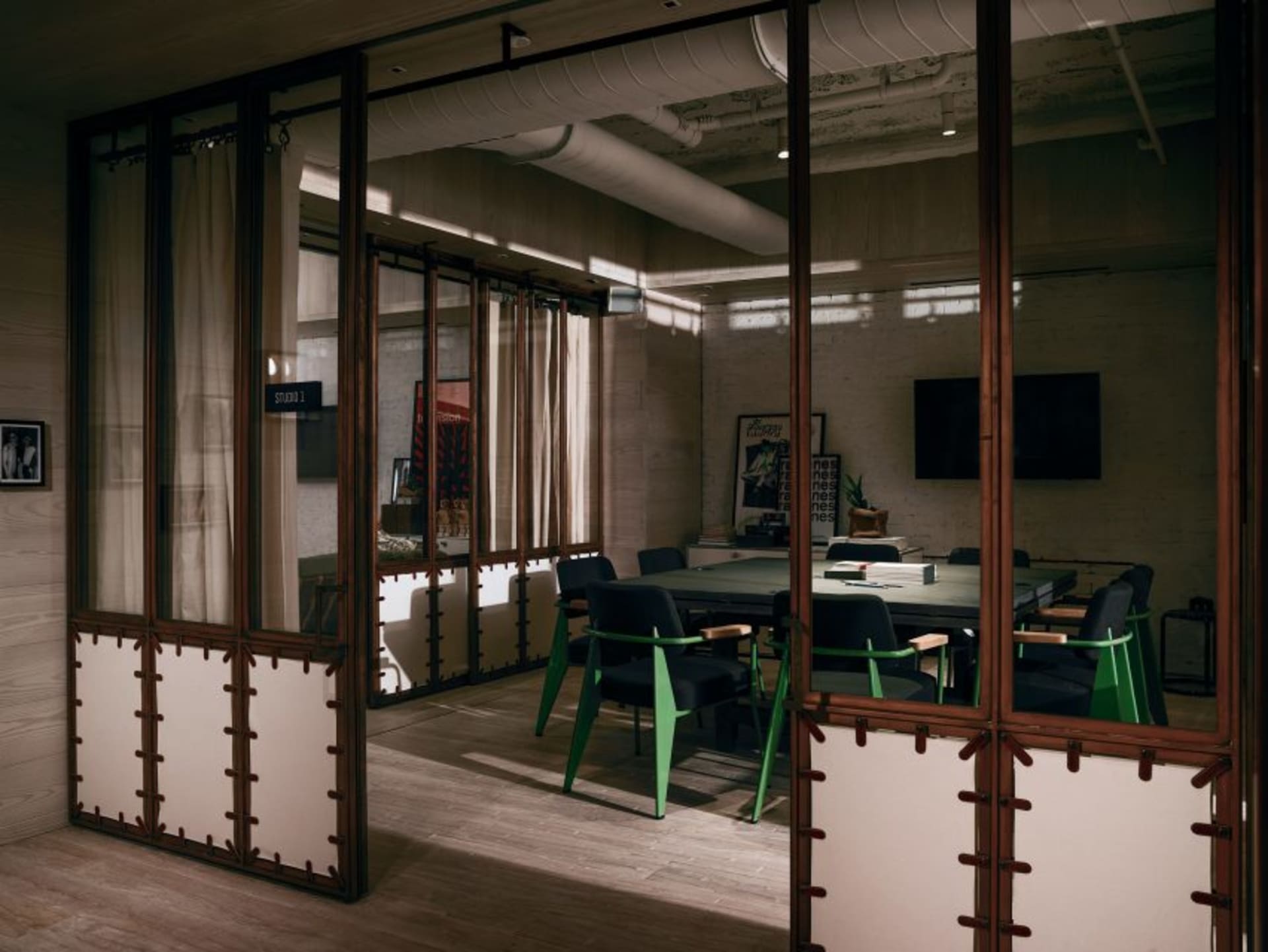 A modern industrial conference room with metal furnishings and glass windows.