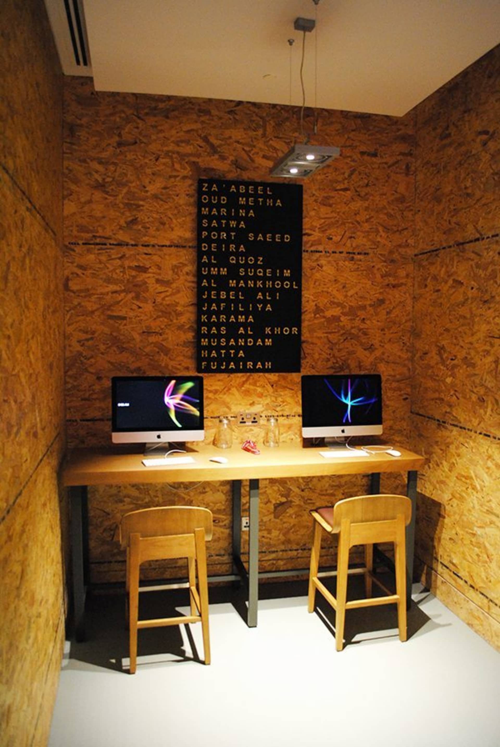 現代簡約的室內工作空間，配有木質桌檯、兩台電腦與高腳凳。