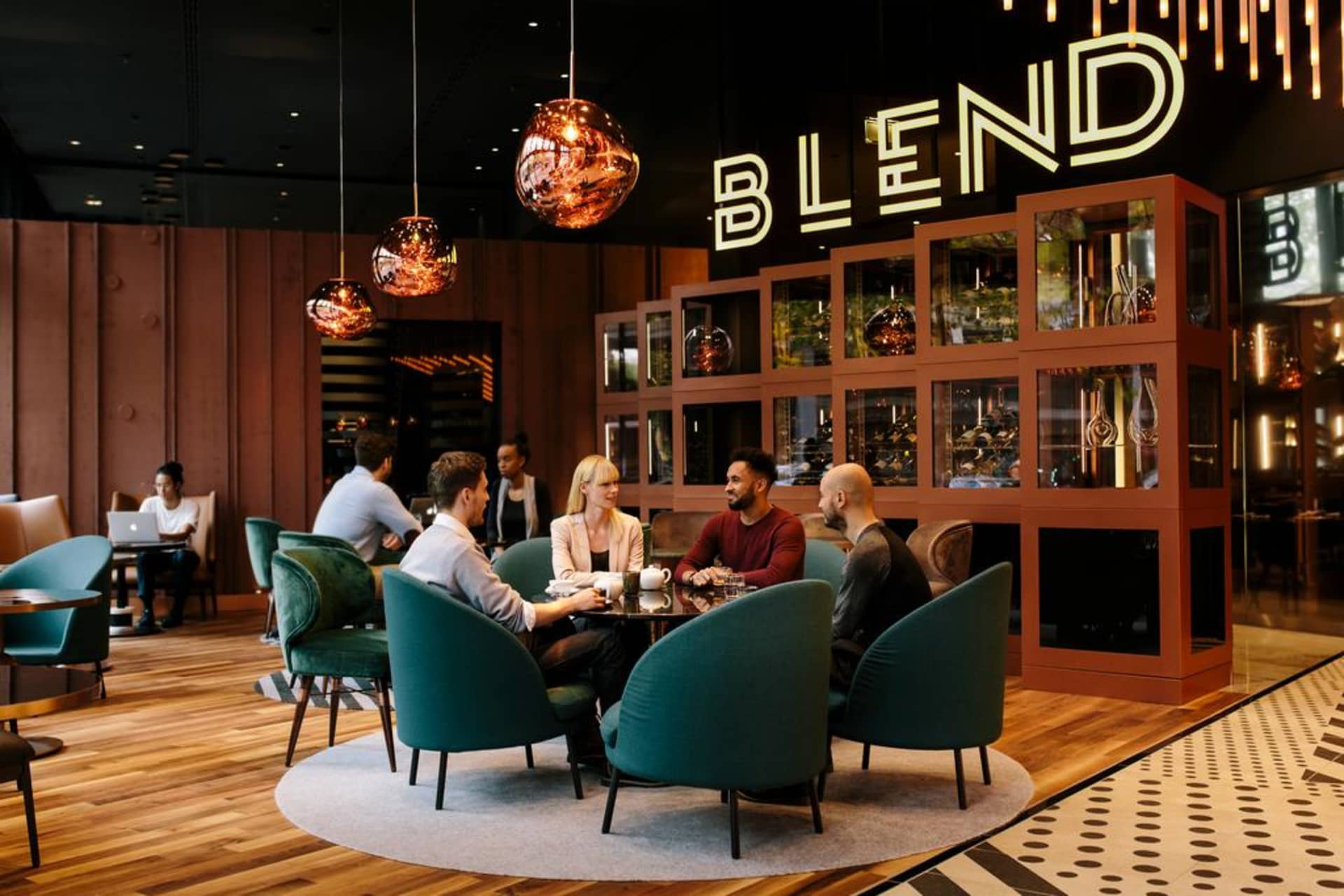 People sitting at a table in a modern restaurant bar with contemporary lighting and seating.