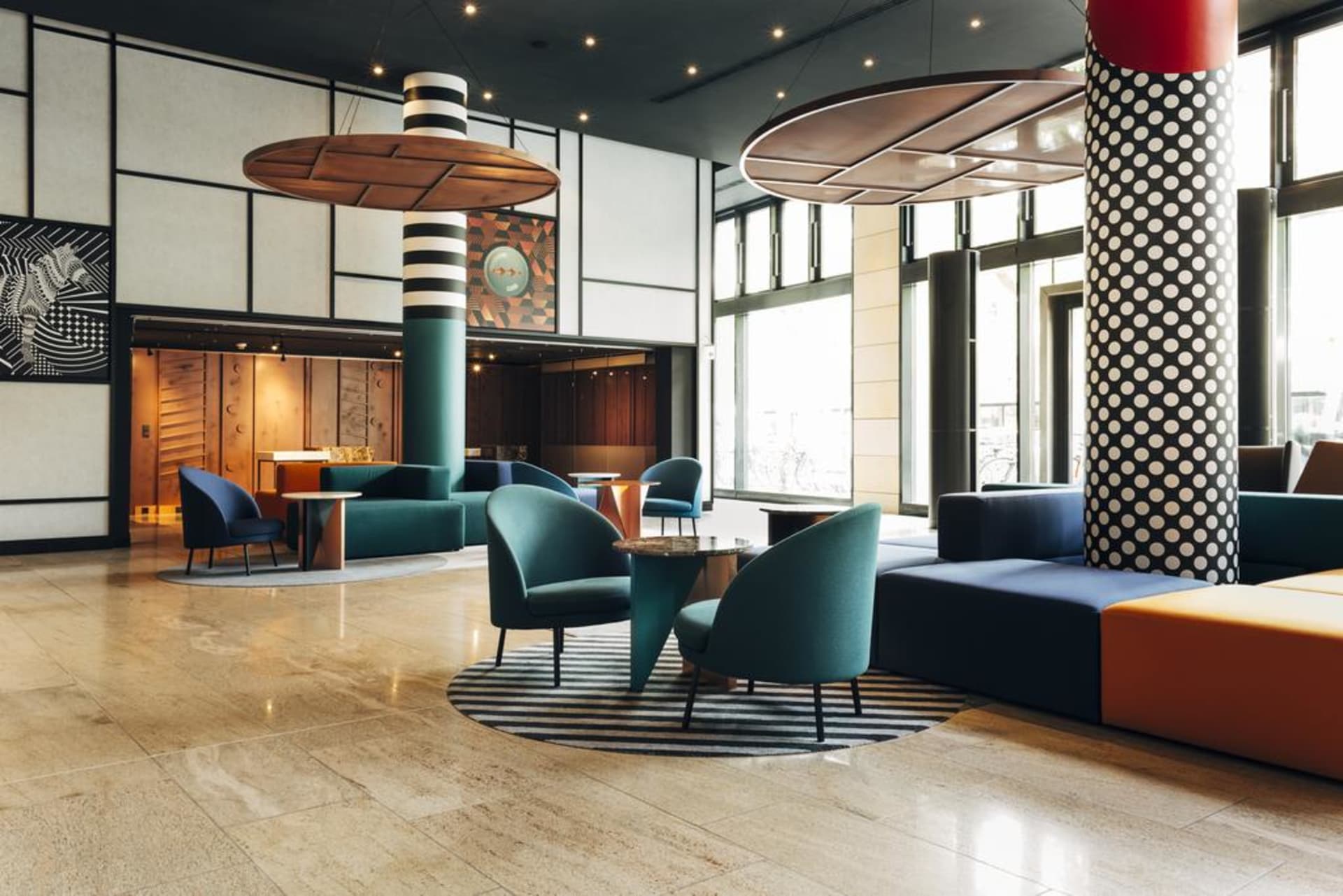 Modern office space featuring concrete columns, leather chairs, metal accents, and glass partitions.