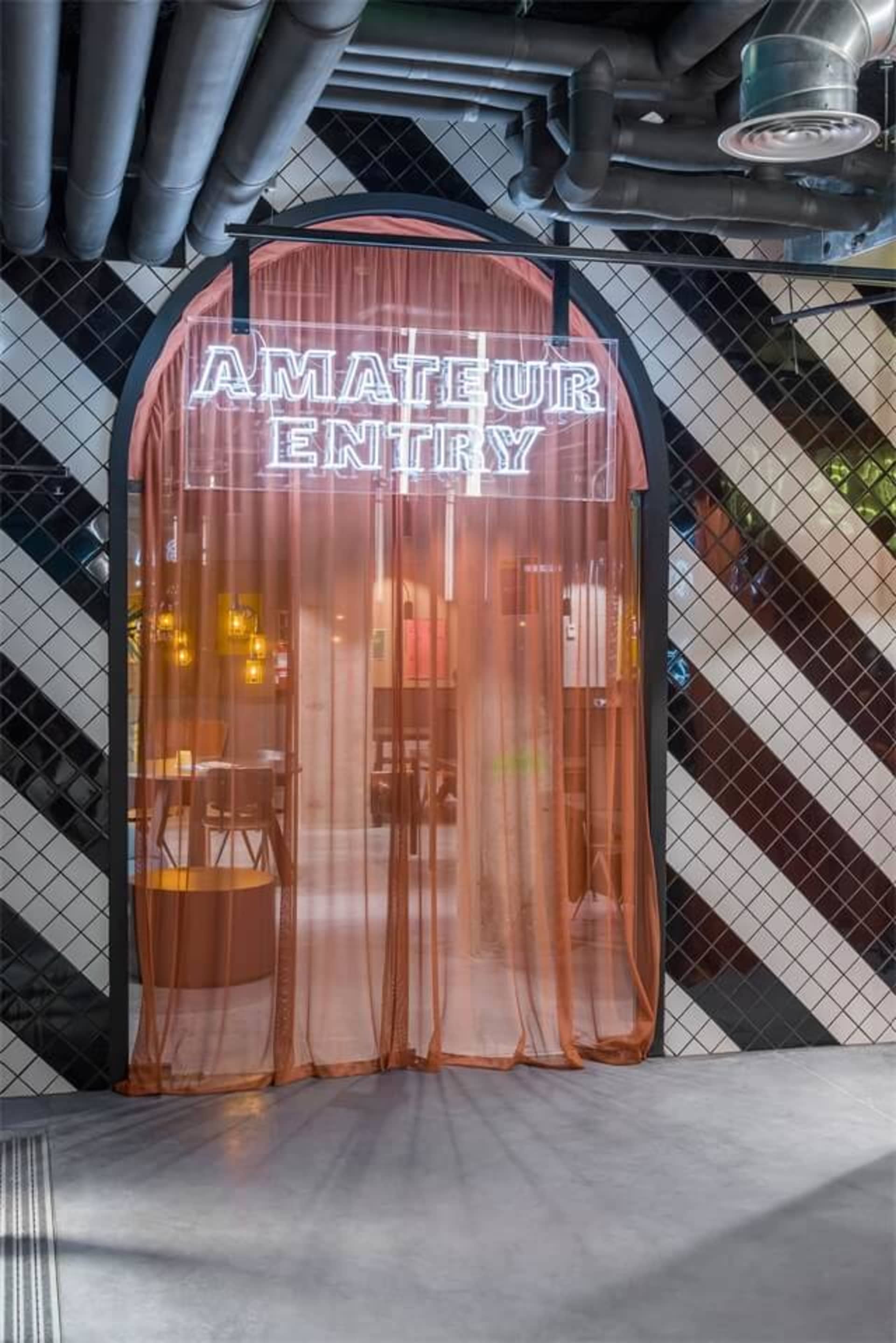 現代玄關設有玻璃簾,搭配發光招牌寫著「Amateur Entry」。