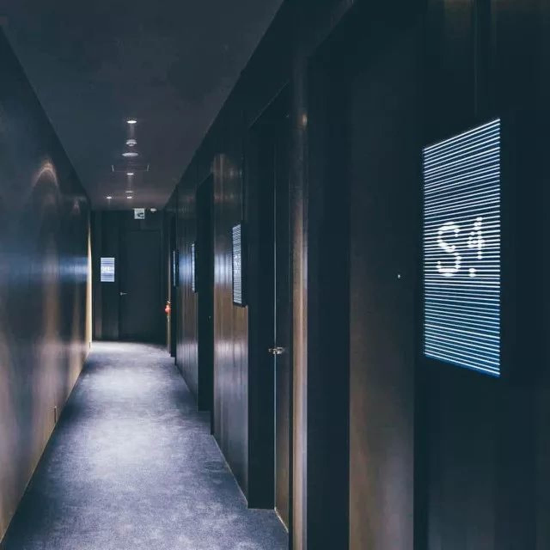 Dark wooden hotel corridor with a digital display panel showing the number 34.