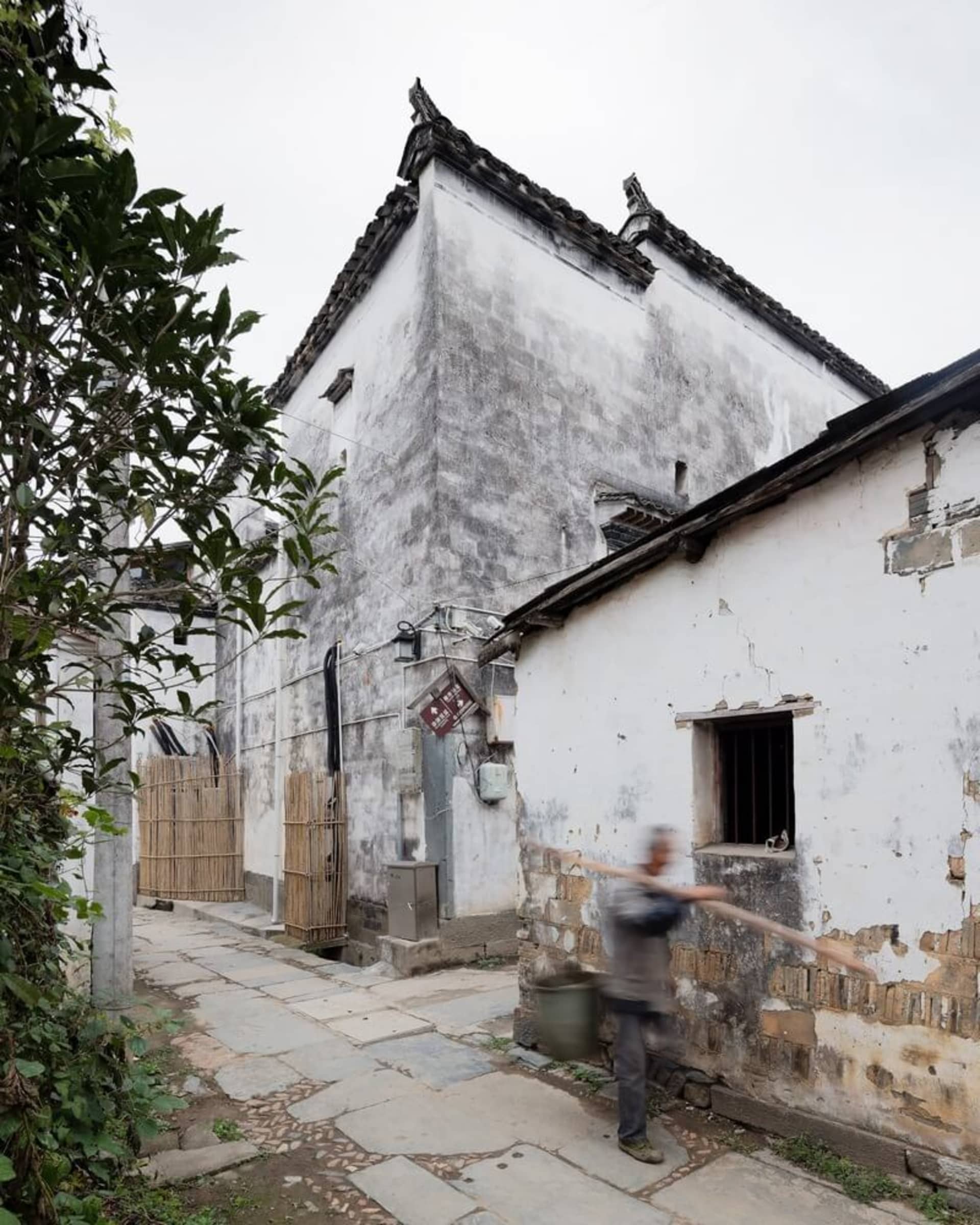 A narrow, urban street with ancient buildings made of concrete and wood.