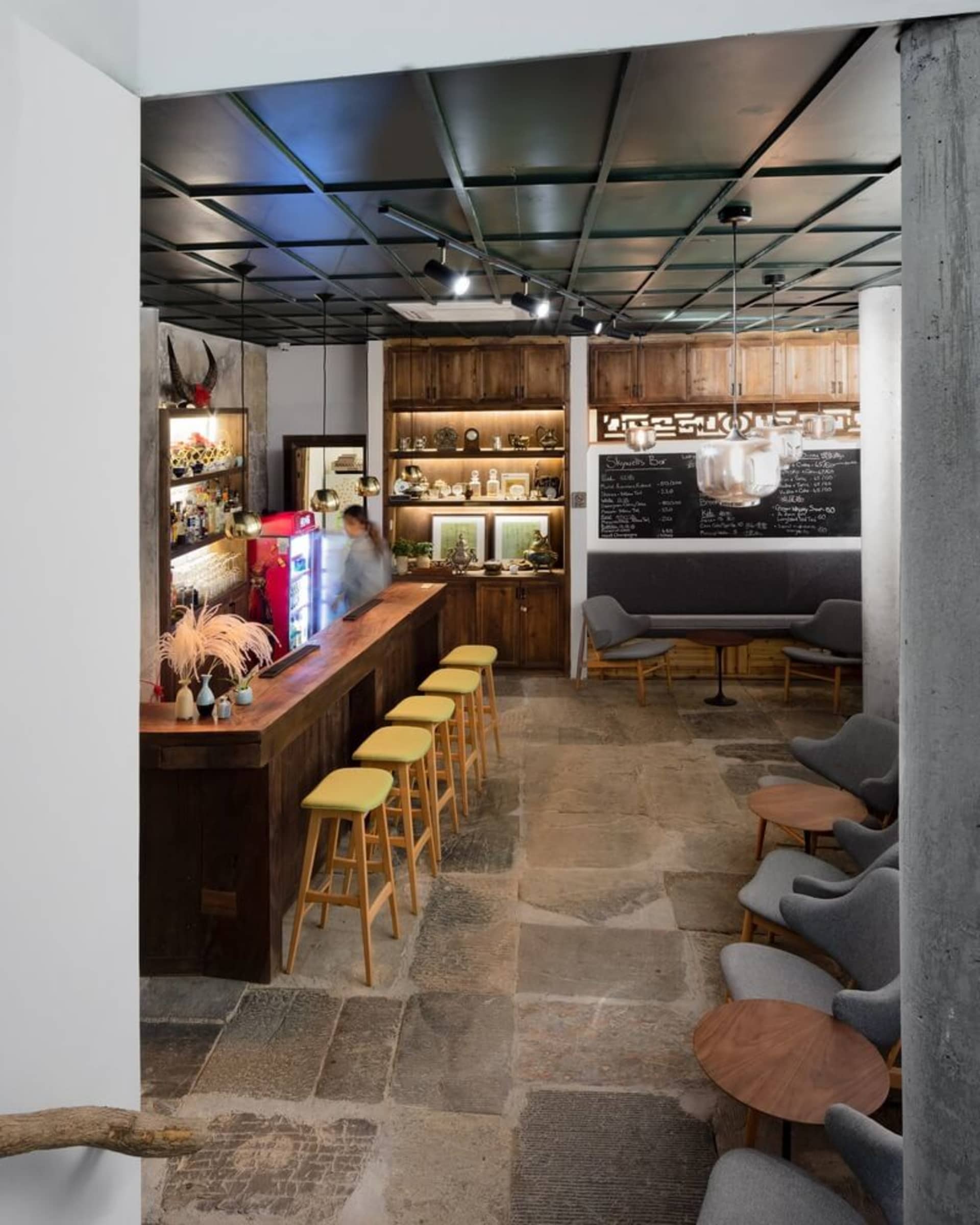 Industrial-style cafe bar with wooden seating, stone flooring, and metal accents