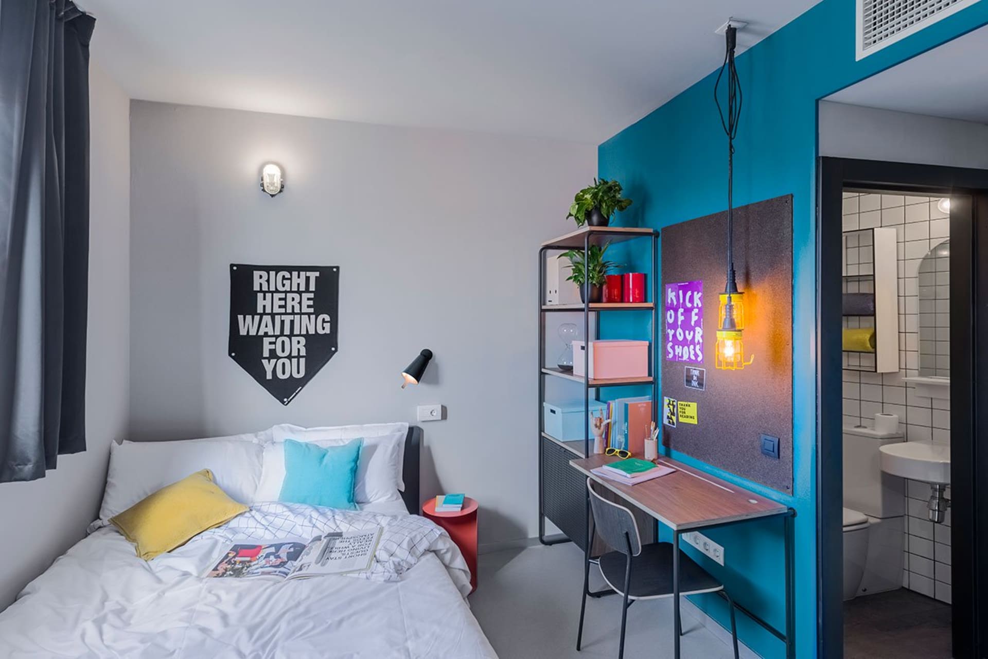 A minimalist bedroom with urban art accents, featuring a neatly made bed with white bedding and colorful throw pillows.