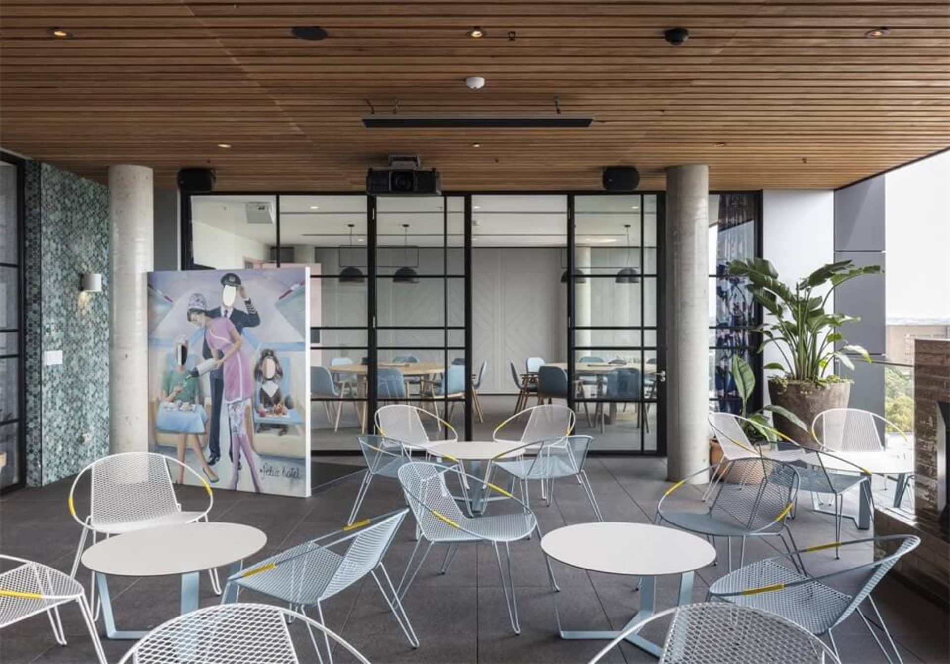 A minimalist office space with metal chairs, glass partitions, concrete flooring, and wooden accents.