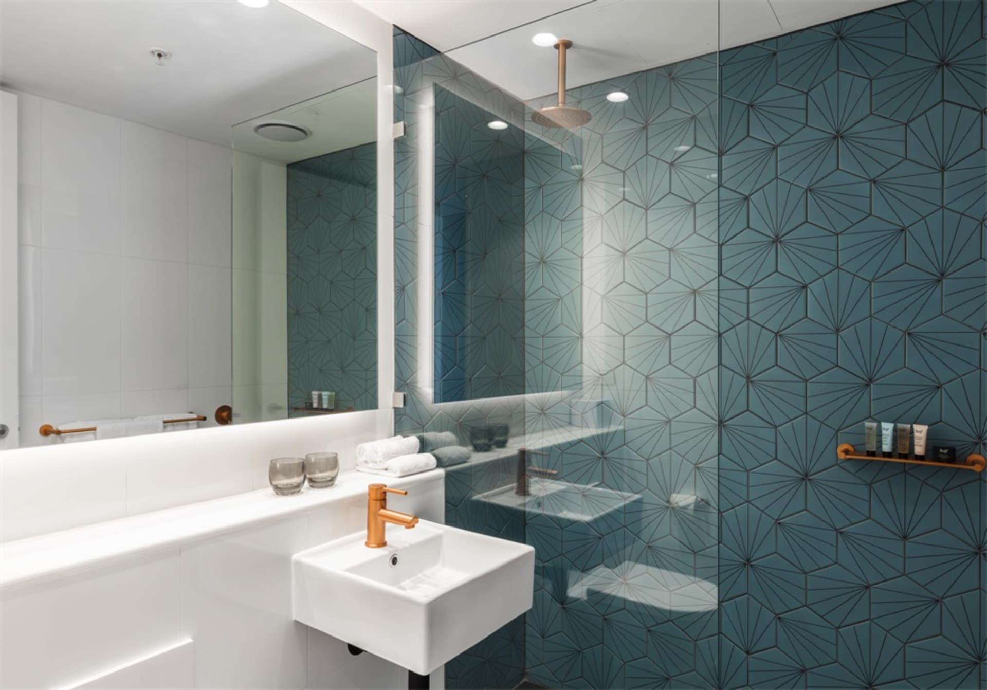 Modern bathroom with blue patterned tiles on the walls and a white sink.