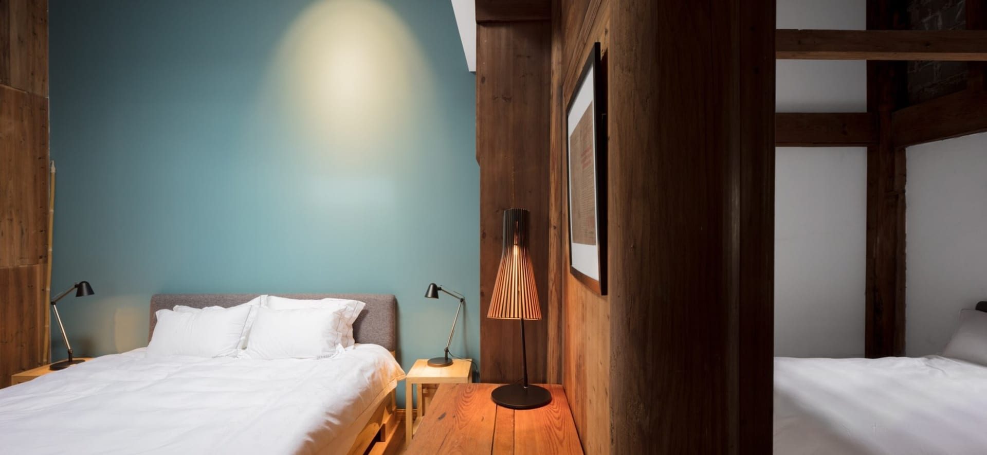 Modern bedroom featuring a white bed, wooden furniture, and a wooden floor.