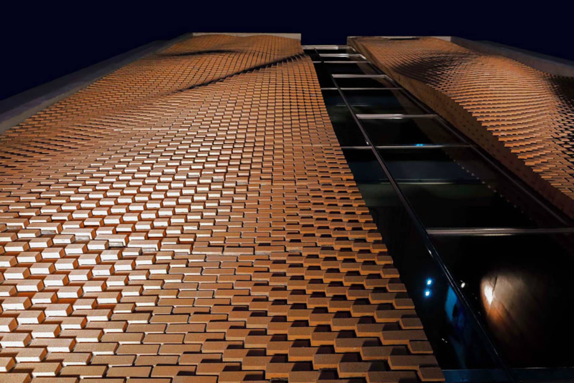 A modern building facade made of a repeating pattern of bricks.