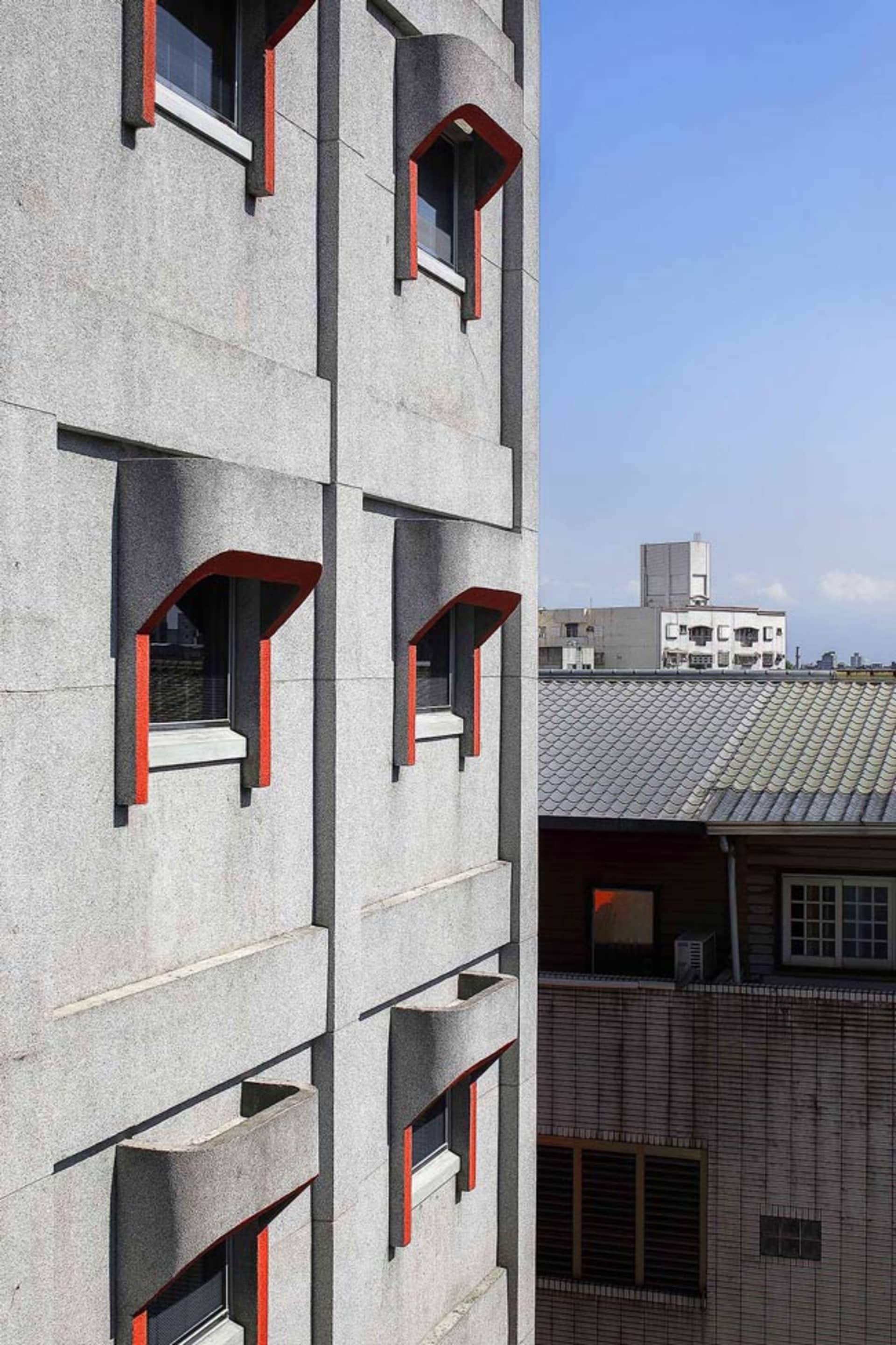 一座現代混凝土建築外觀，帶有紅色點綴。