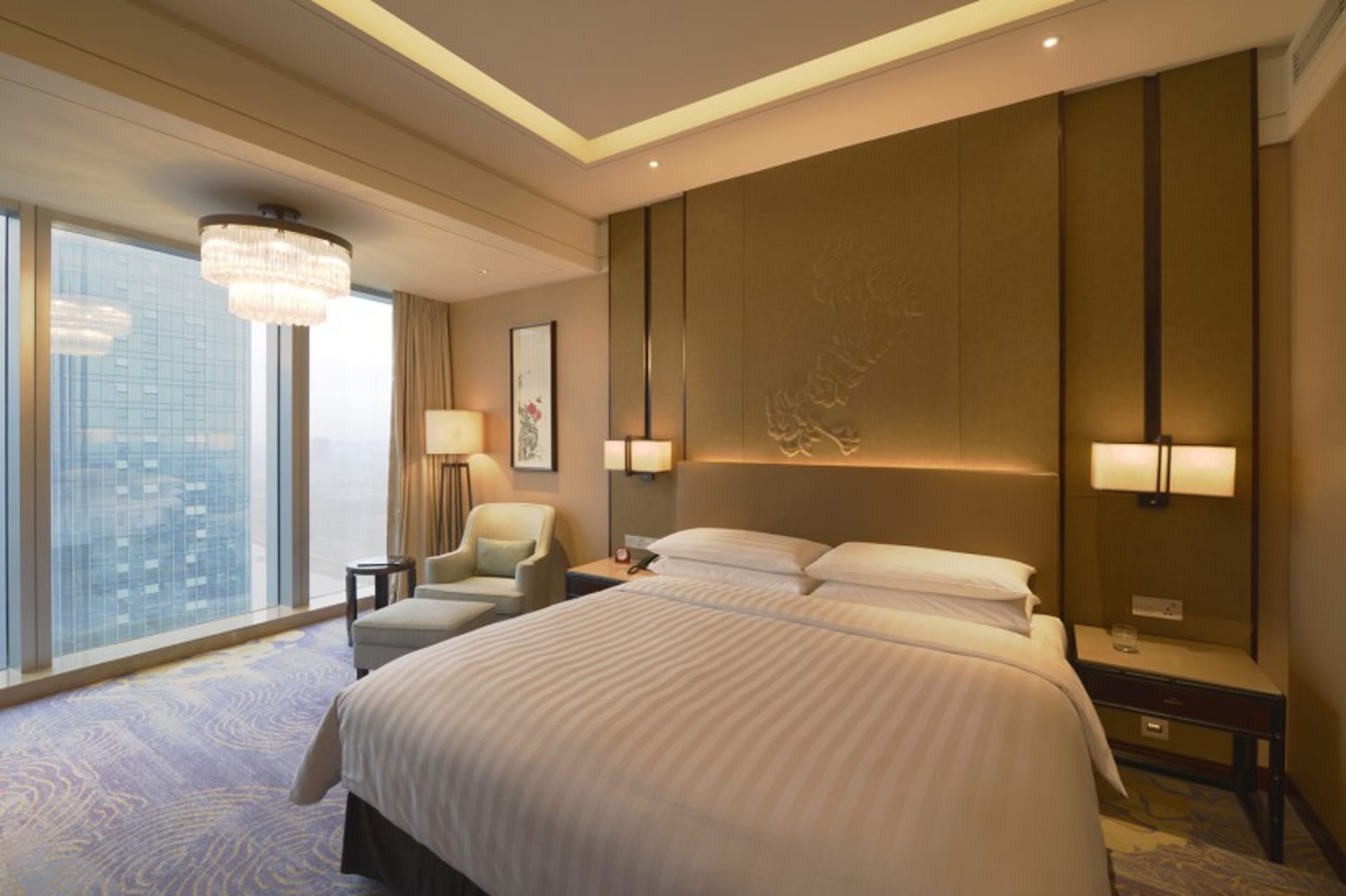 Luxurious modern hotel room with a king bed, floor-to-ceiling windows, and elegant lighting fixtures.