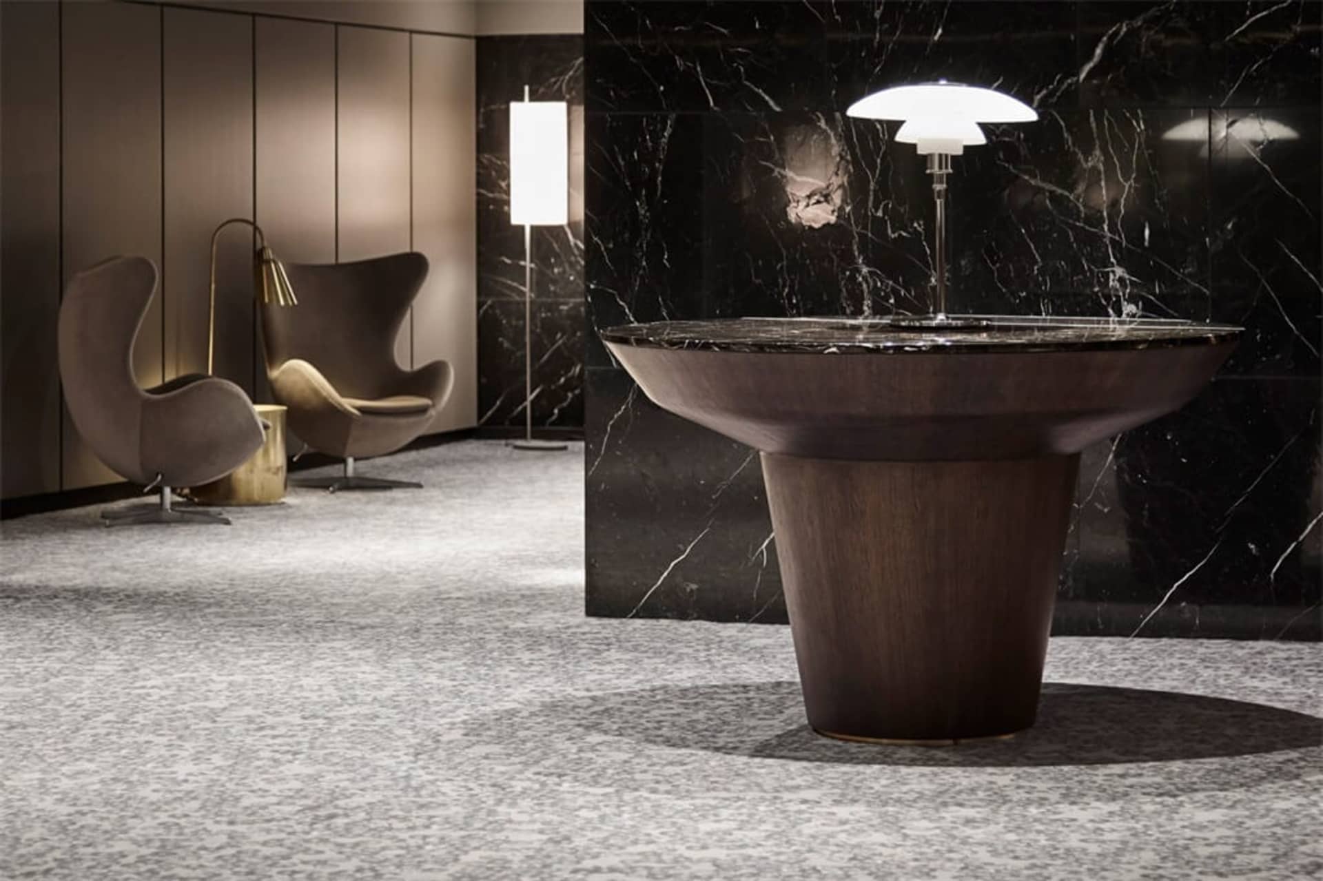 A modern interior design featuring a wooden table with a marble top and a marble wall.