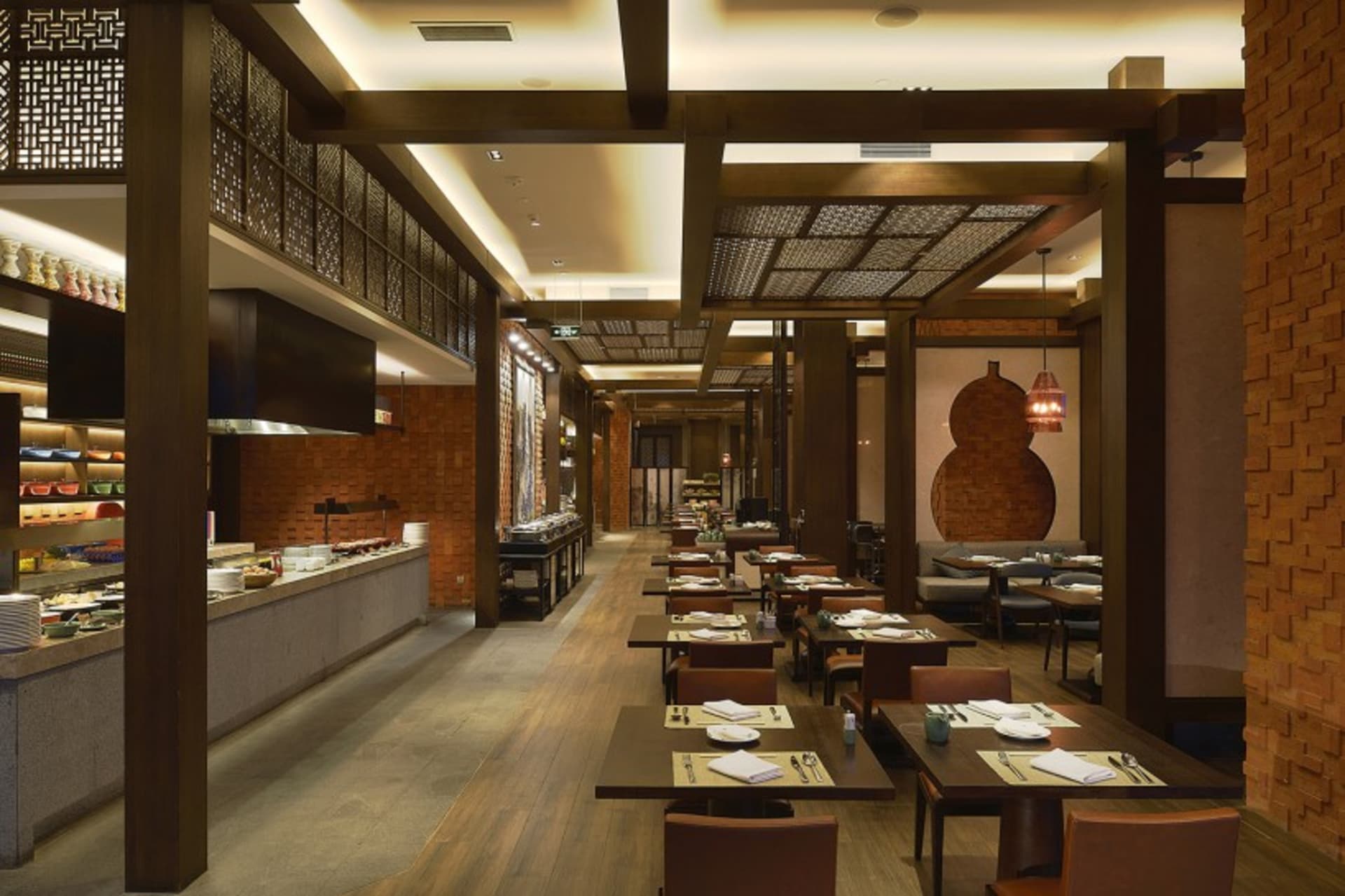 Modern kitchen area with brick walls and wooden floors, featuring a long dining table, chairs, and a variety of dining setups