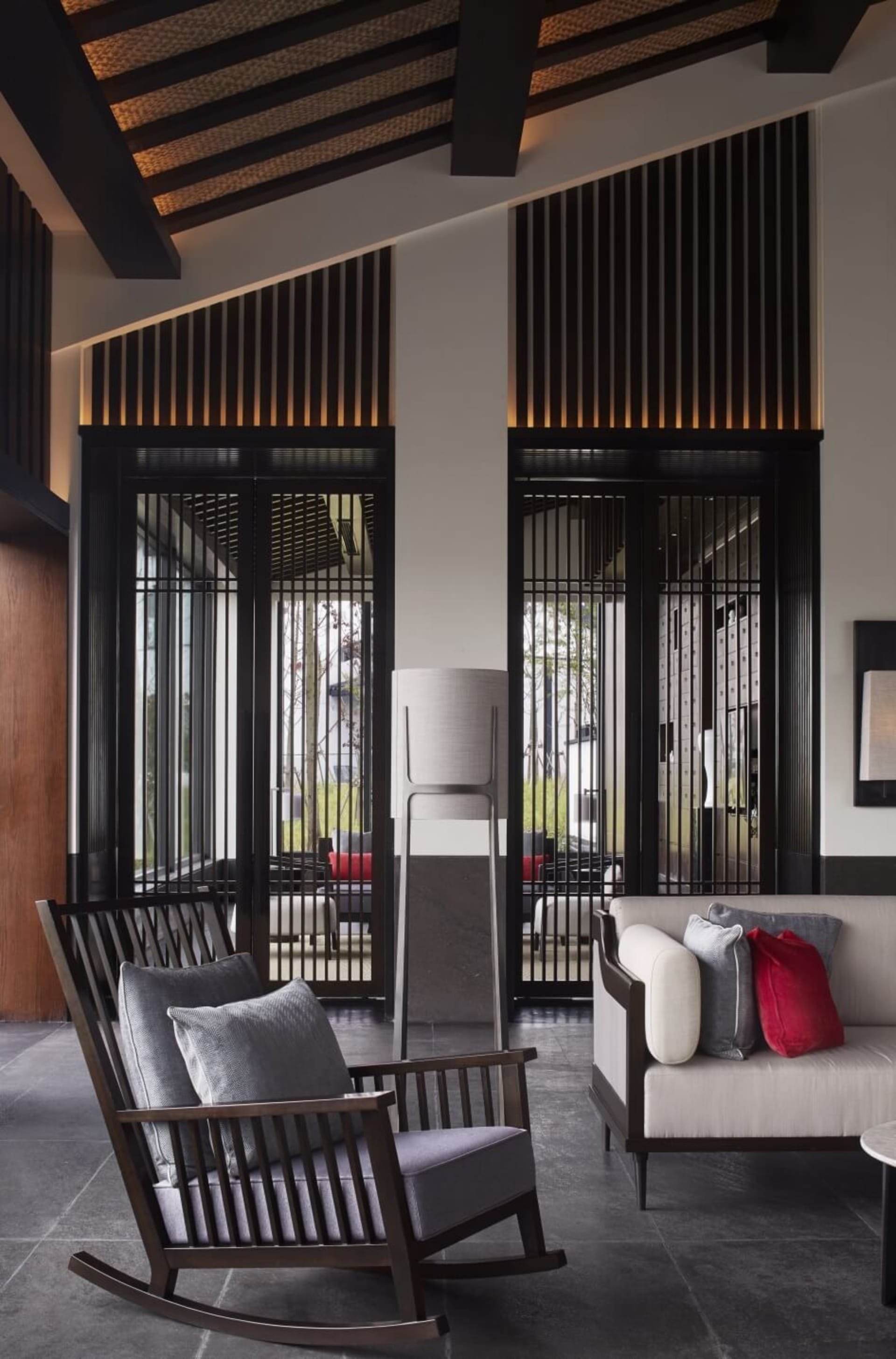 Modern living room featuring contemporary furnishings with wooden rocking chair, metal sofa, and glass elements.