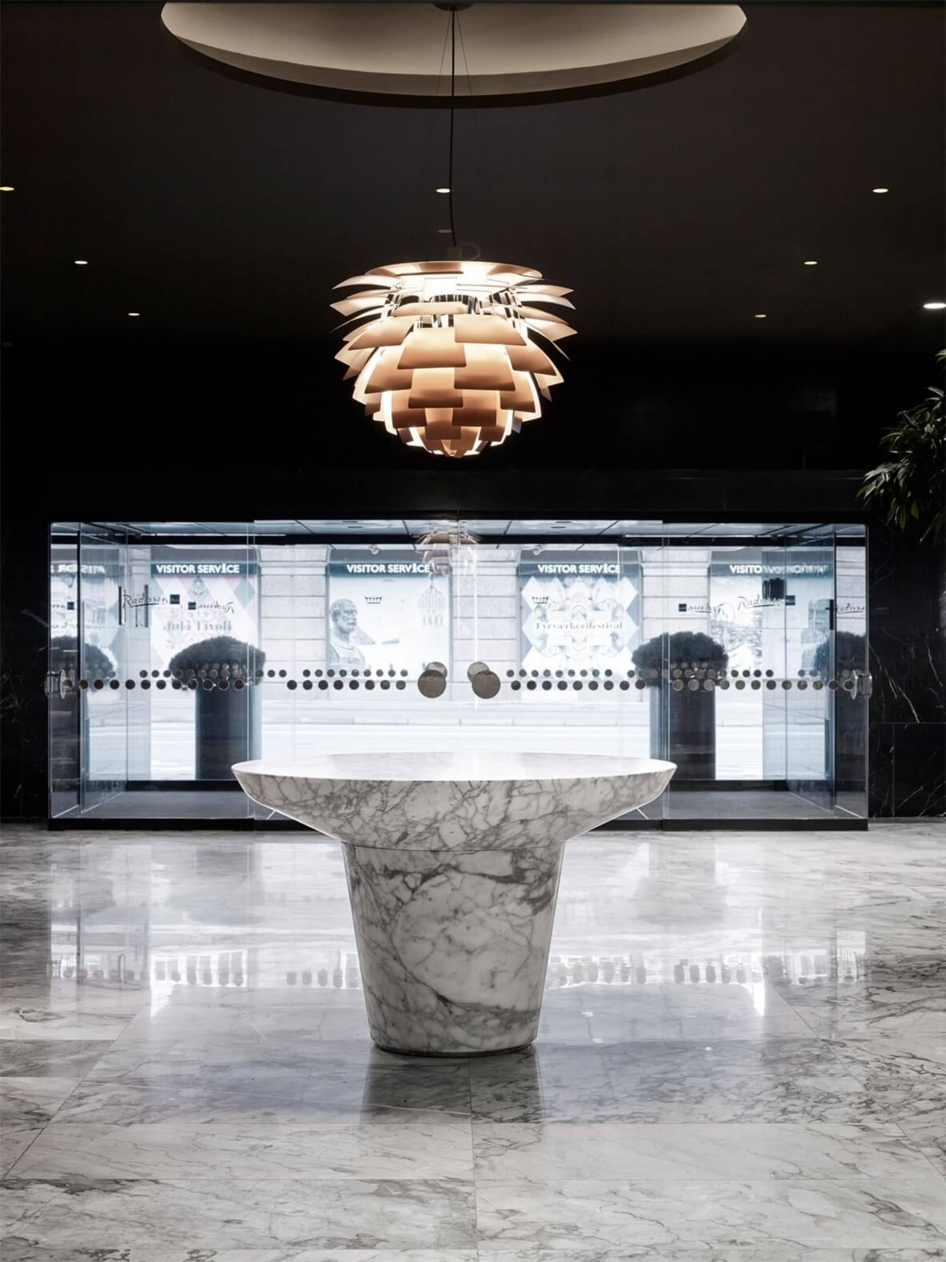 Modern lobby interior with marble table and glass walls.