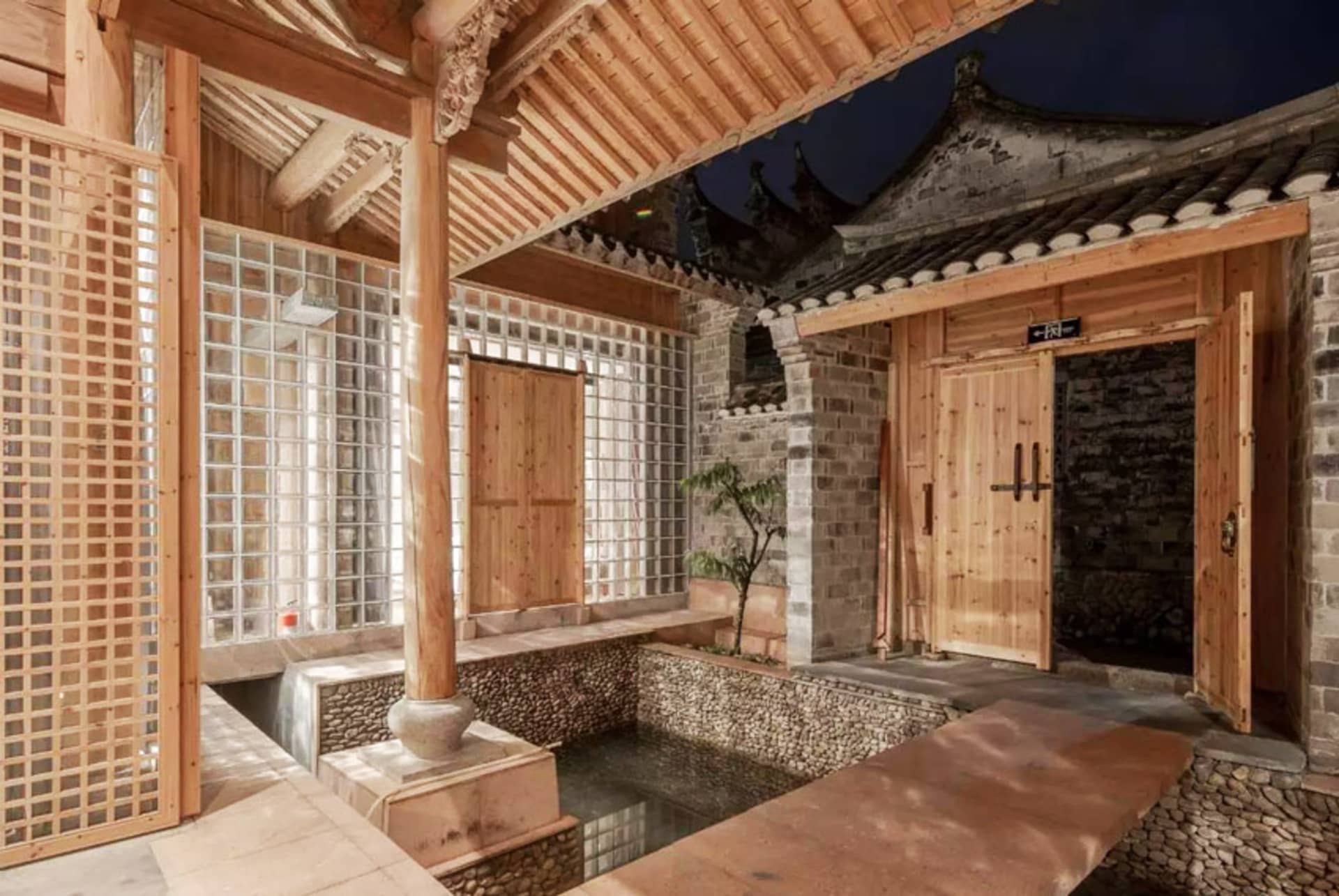 Traditional Chinese courtyard with wooden structures, glass walls, and stone elements.