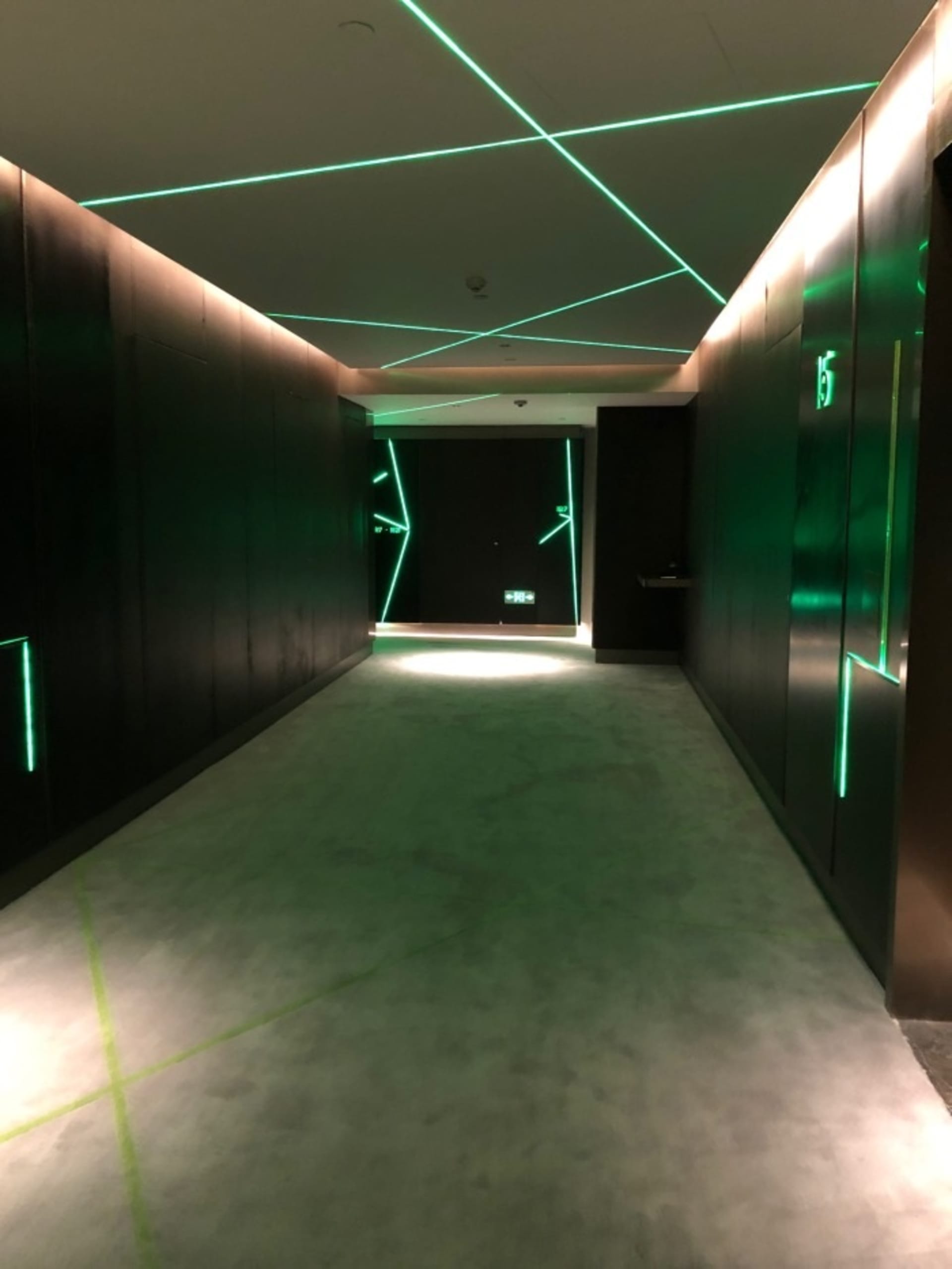 現代室內走廊,搭配金屬包覆牆面與綠色燈光線條照明。