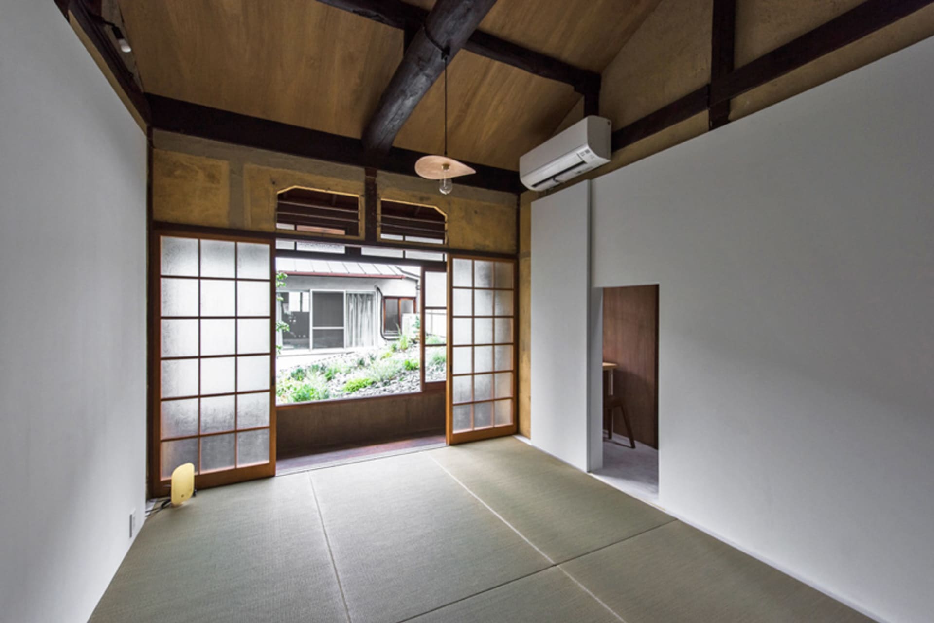 A minimalist residential interior featuring wooden walls, paper floors, and a paper air conditioning unit.